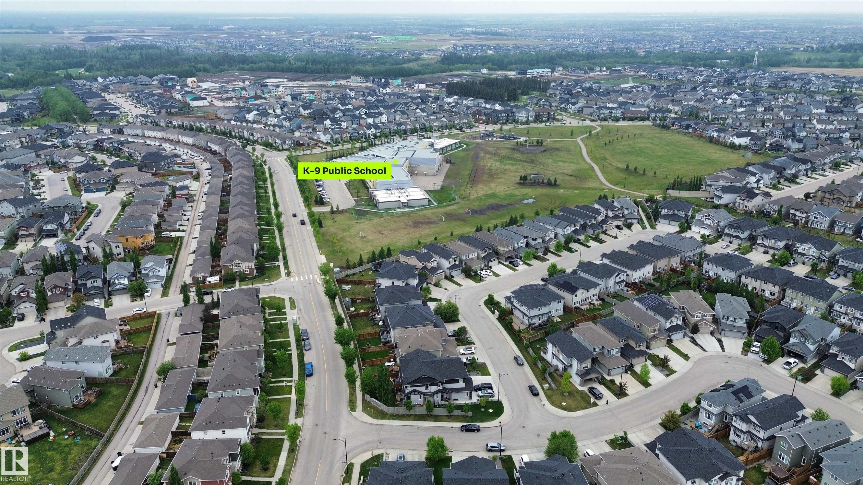 Aerial perspective showcasing a residential development with a K-9 Public School, extensive green spaces, and organized street patterns - 3962 Claxton Loop, Edmonton, AB - Outdoor With View