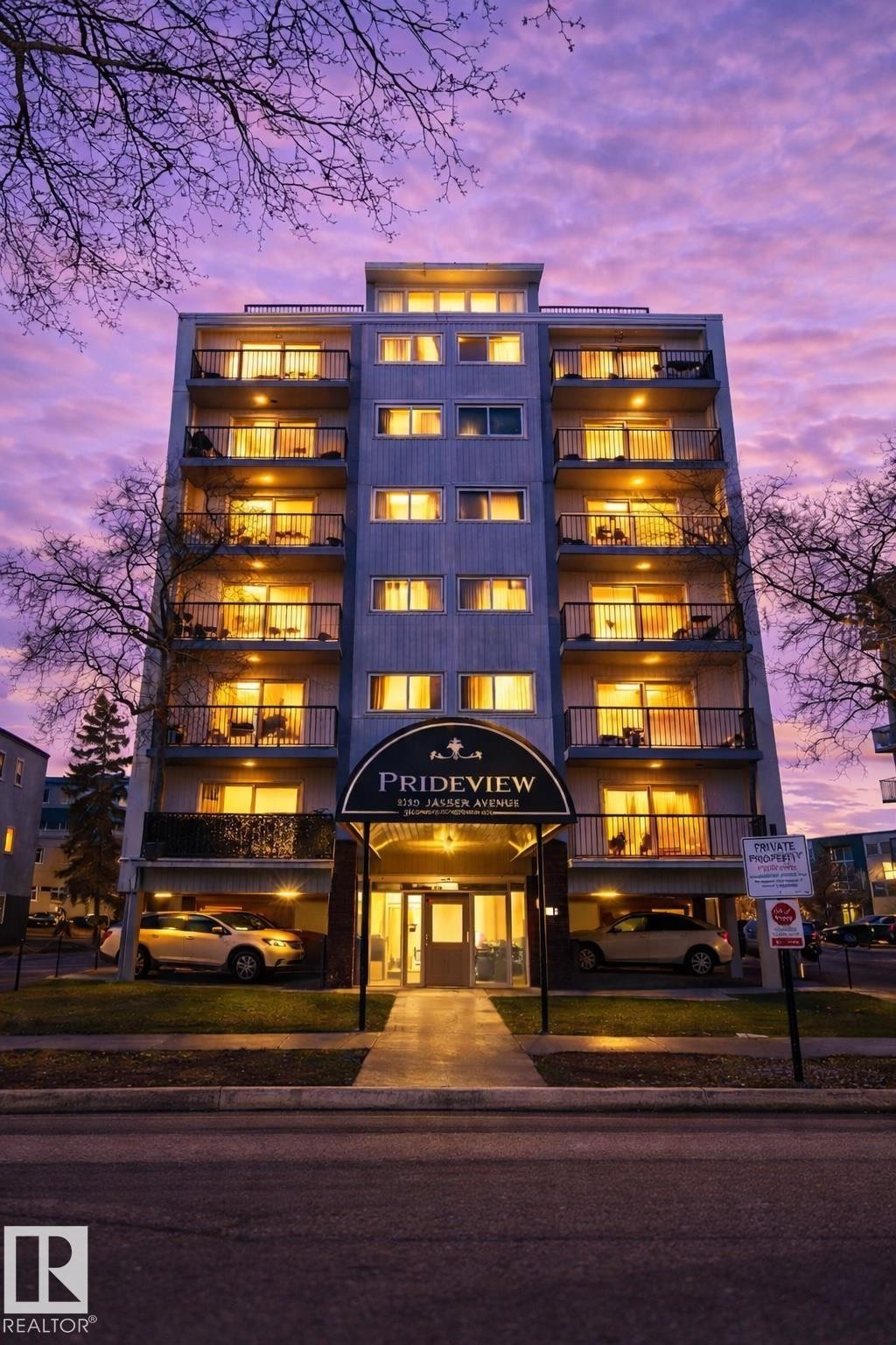 Modern multi-story building featuring individual balconies with black railings, a covered main entrance with signage, and integrated ground-level parking - 202 8310 Jasper Avenue, Edmonton, AB - Indoor Photo Showing Other Room