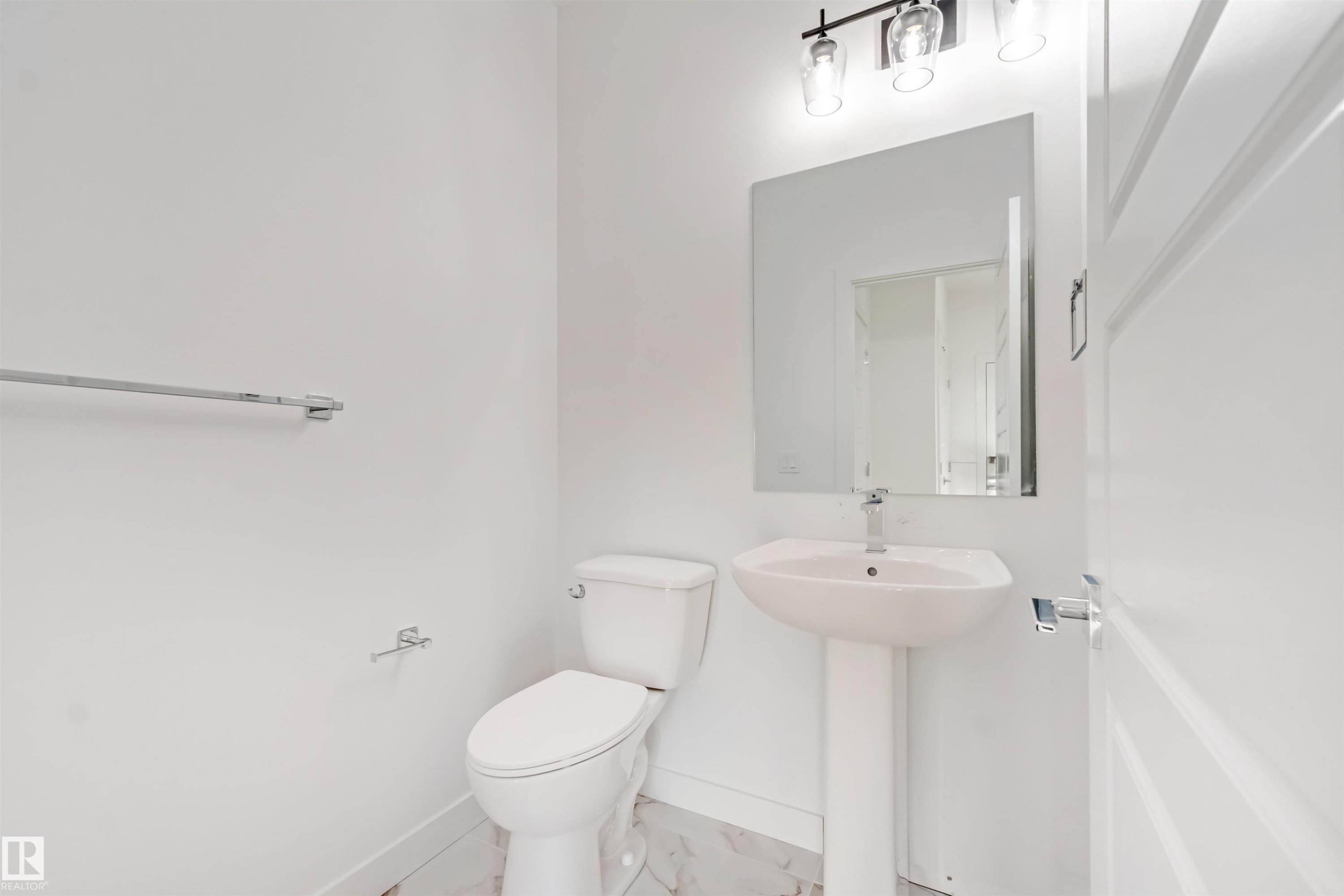 Pedestal sink with a polished chrome faucet, rectangular mirror, and three-light vanity fixture - 1511 211 Street Nw, Edmonton, AB