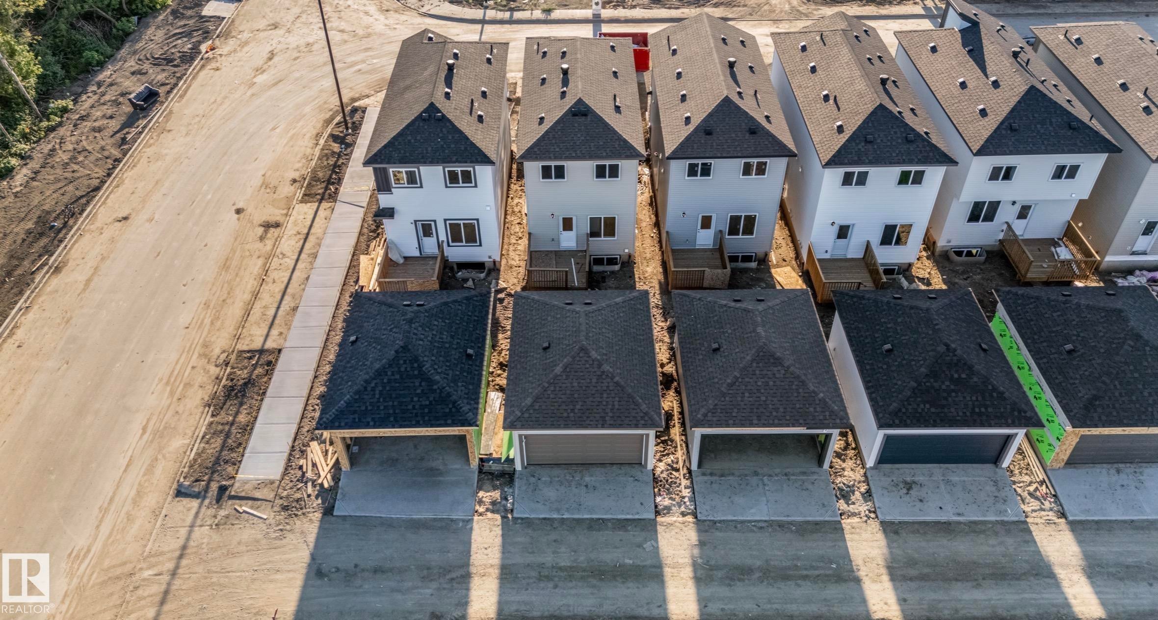 Newly constructed homes featuring attached garages, dark shingle roofs, and light-colored siding - 1511 211 Street Nw, Edmonton, AB