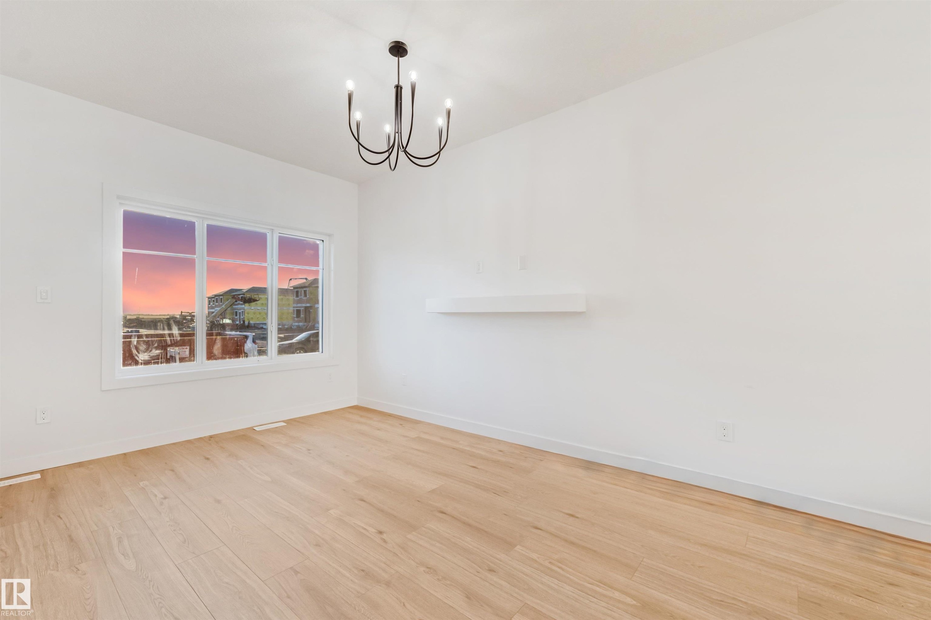 Recessed lighting, wood-finish flooring, white walls, and a contemporary black chandelier create a refined interior - 1511 211 Street Nw, Edmonton, AB