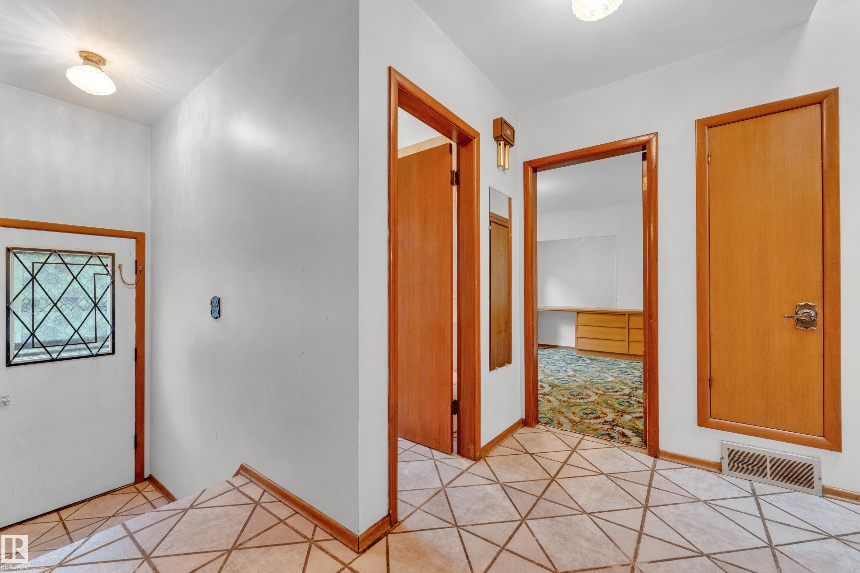 Foyer with geometric tile flooring, white walls, and warm wood trim - 10819 54 Avenue, Edmonton, AB