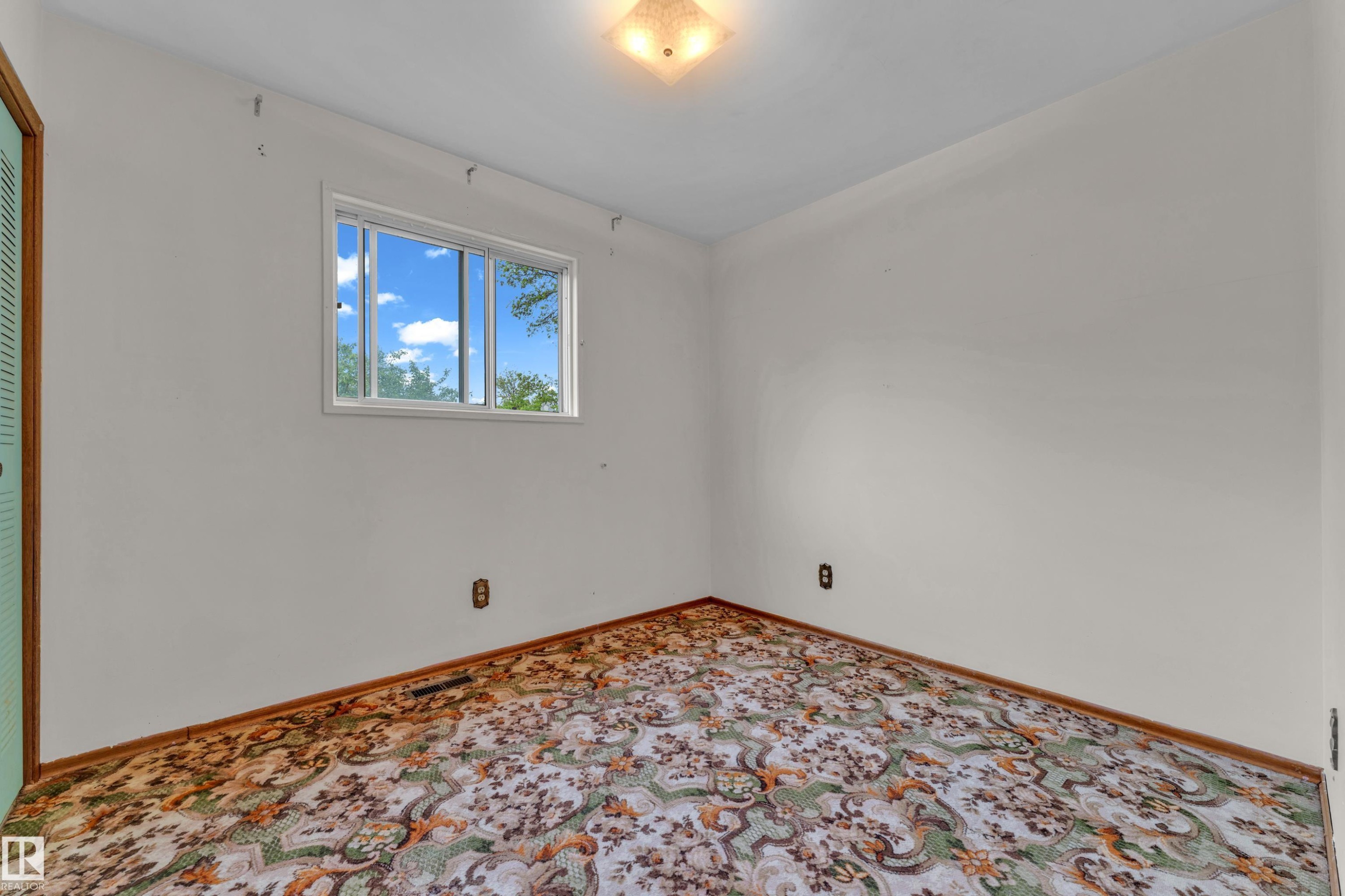 Bright interior space featuring a multi-pane window, white walls, and a patterned carpet - 10819 54 Avenue, Edmonton, AB