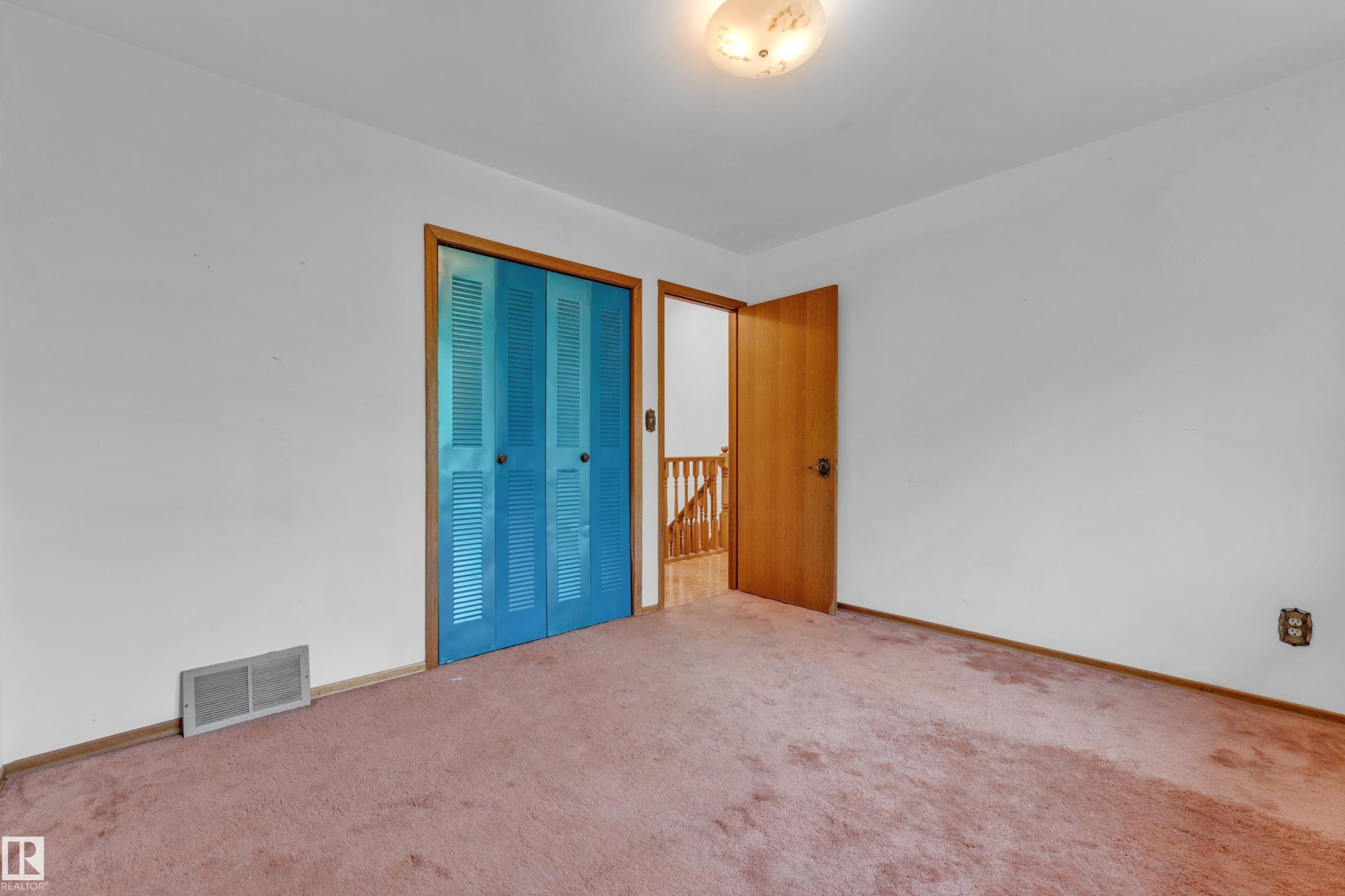 Interior room featuring a flush-mount ceiling light fixture, white walls, and pink carpet flooring - 10819 54 Avenue, Edmonton, AB