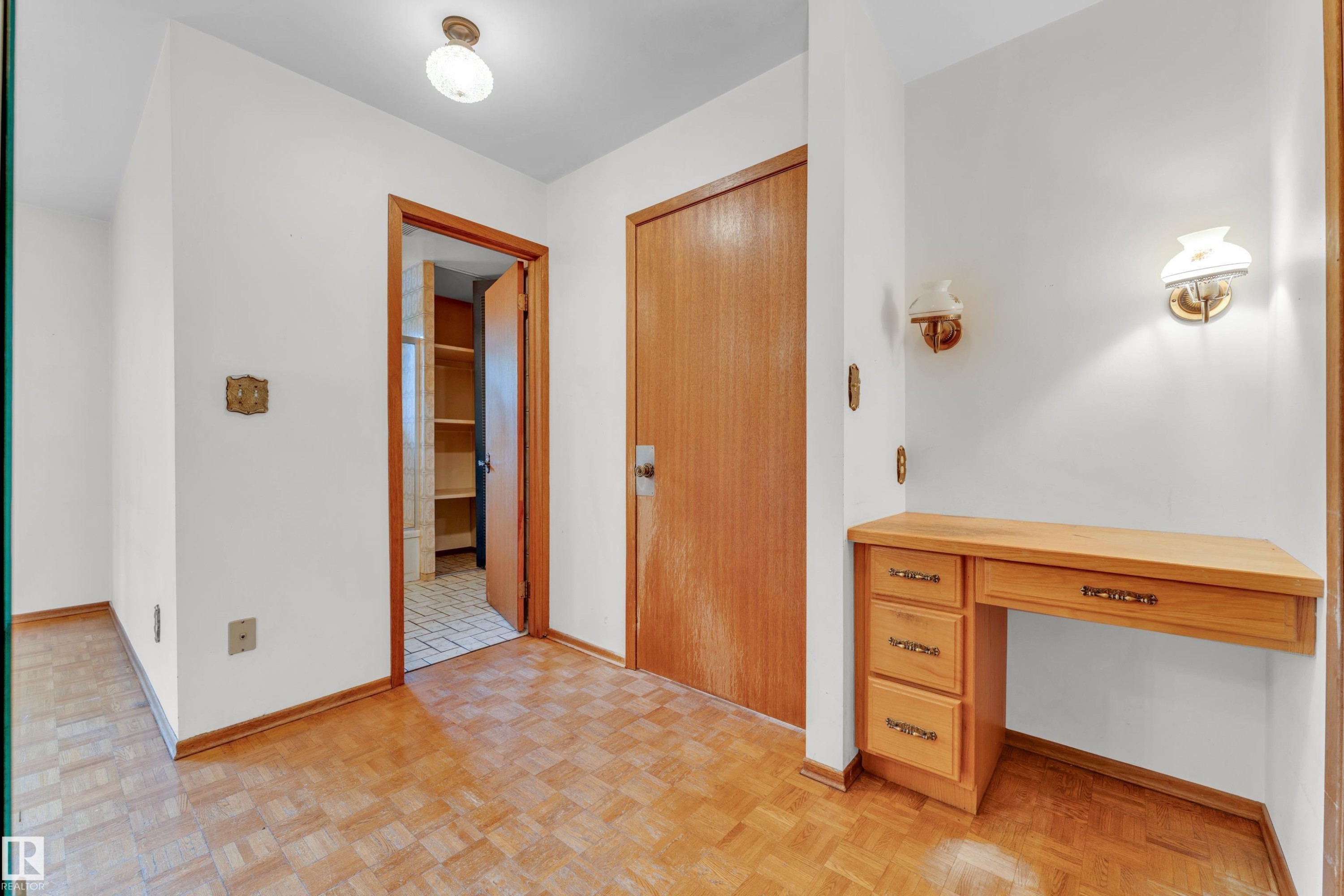 Entryway featuring wood-finish parquet flooring and a built-in wooden desk with drawers - 10819 54 Avenue, Edmonton, AB