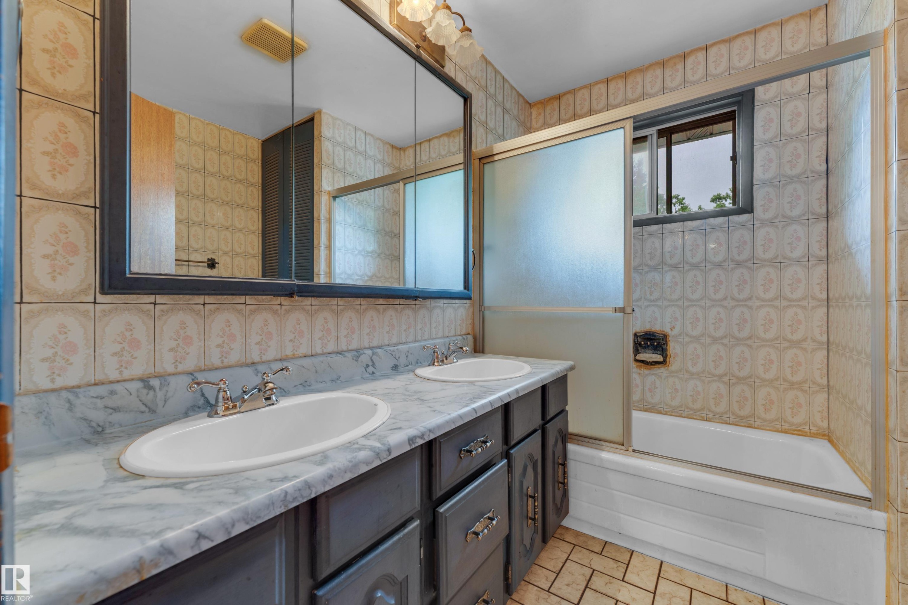Bathroom vanity featuring dual inset sinks, a marbled countertop, and dark cabinetry with silver hardware - 10819 54 Avenue, Edmonton, AB