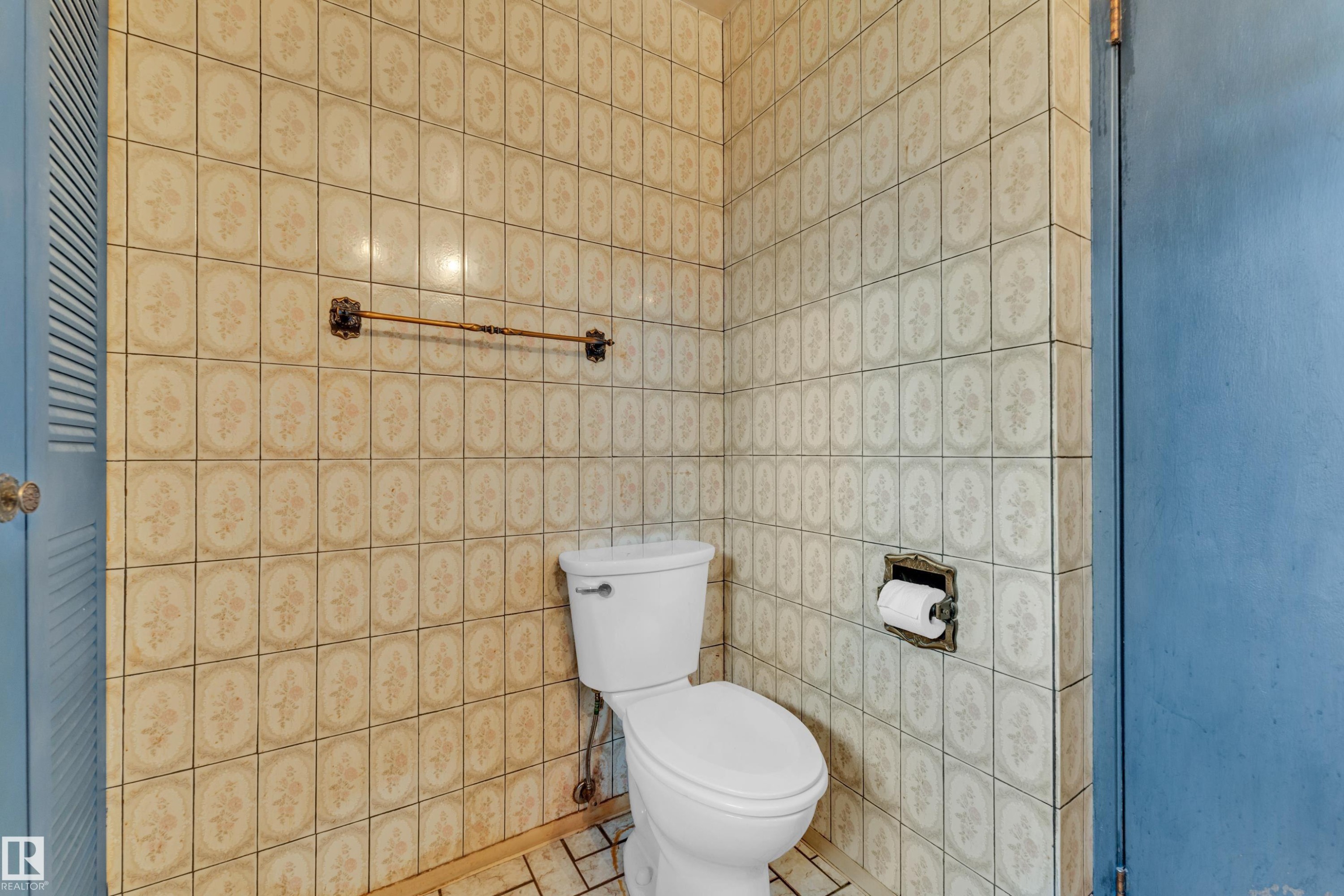 Bathroom featuring floor-to-ceiling decorative wall tiling and a white toilet - 10819 54 Avenue, Edmonton, AB