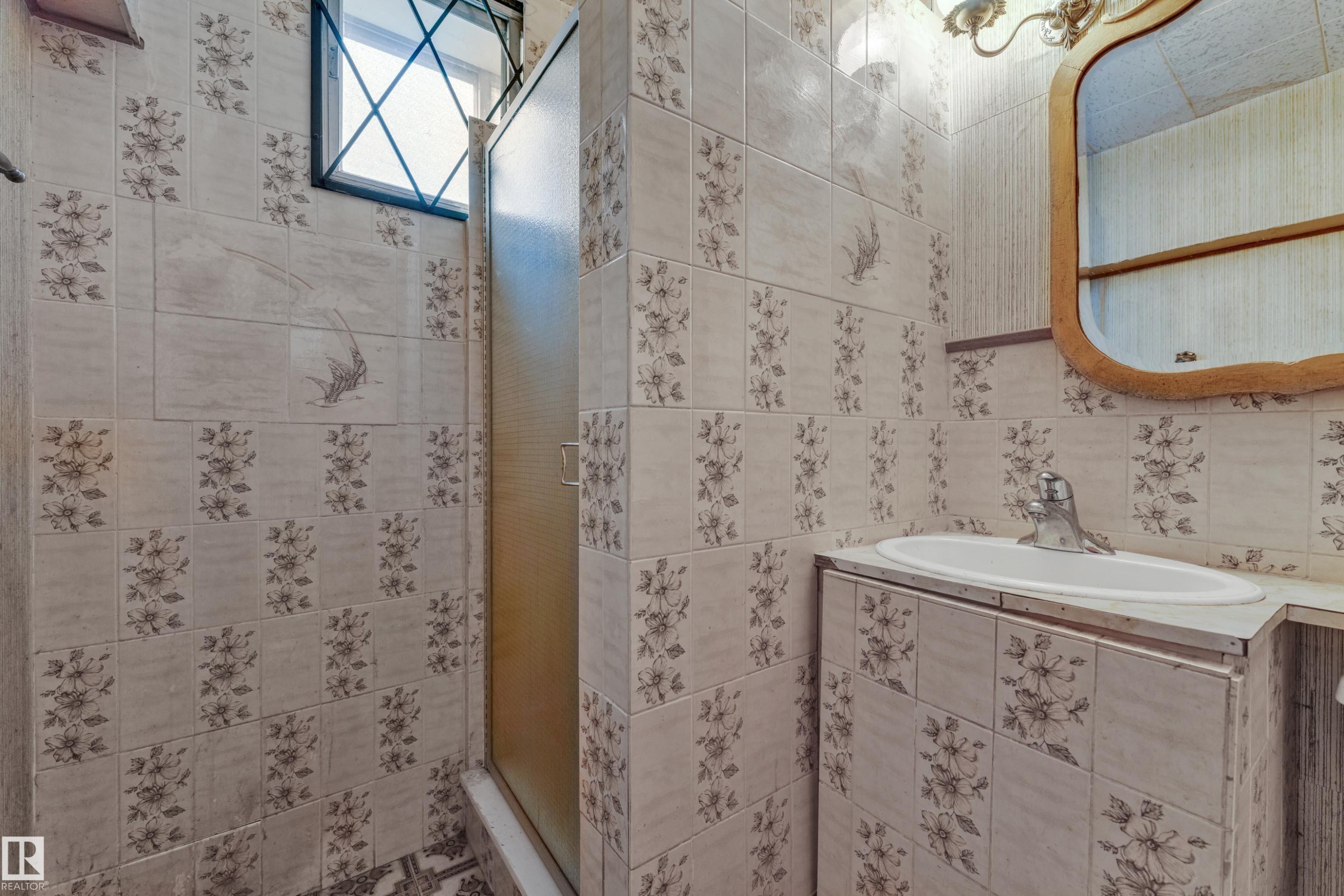 Bathroom featuring floral-patterned wall tiles and a white ceramic sink - 10819 54 Avenue, Edmonton, AB