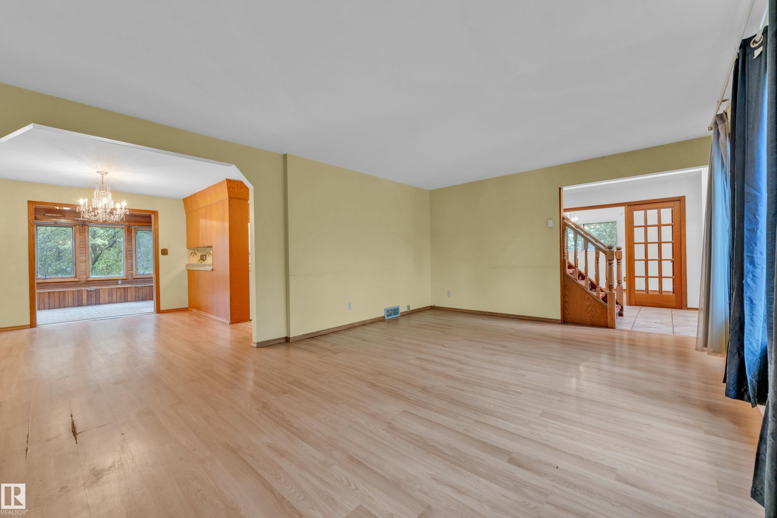 Spacious living area featuring light wood-finish flooring, a neutral wall palette, and recessed lighting - 10819 54 Avenue, Edmonton, AB