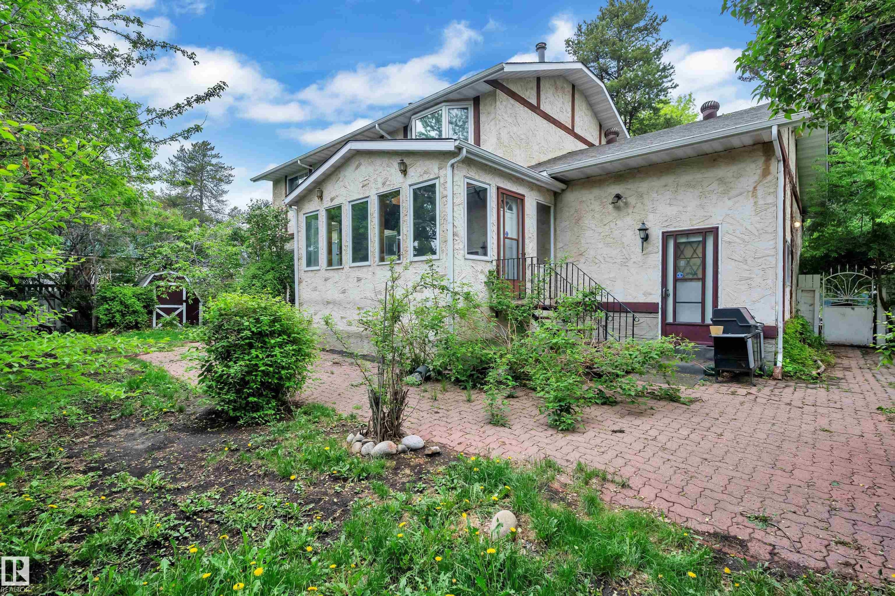 Stucco exterior residence with a sunroom featuring multiple windows - 10819 54 Avenue, Edmonton, AB
