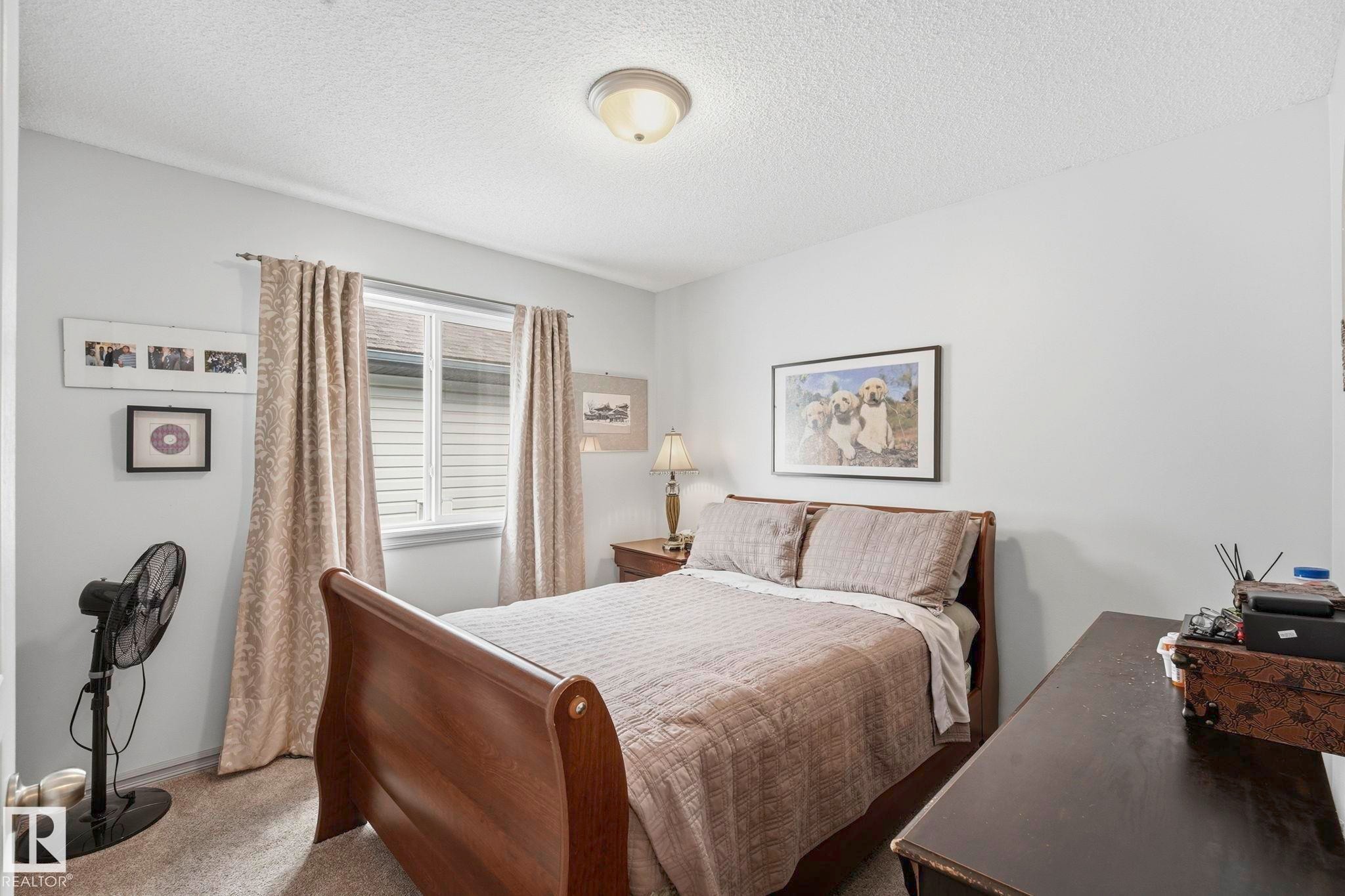 Carpeted bedroom featuring a double-pane window with blinds, ceiling-mounted light fixture, and light-toned walls - 3231 28A Avenue Nw, Edmonton, AB - Indoor Photo Showing Bedroom