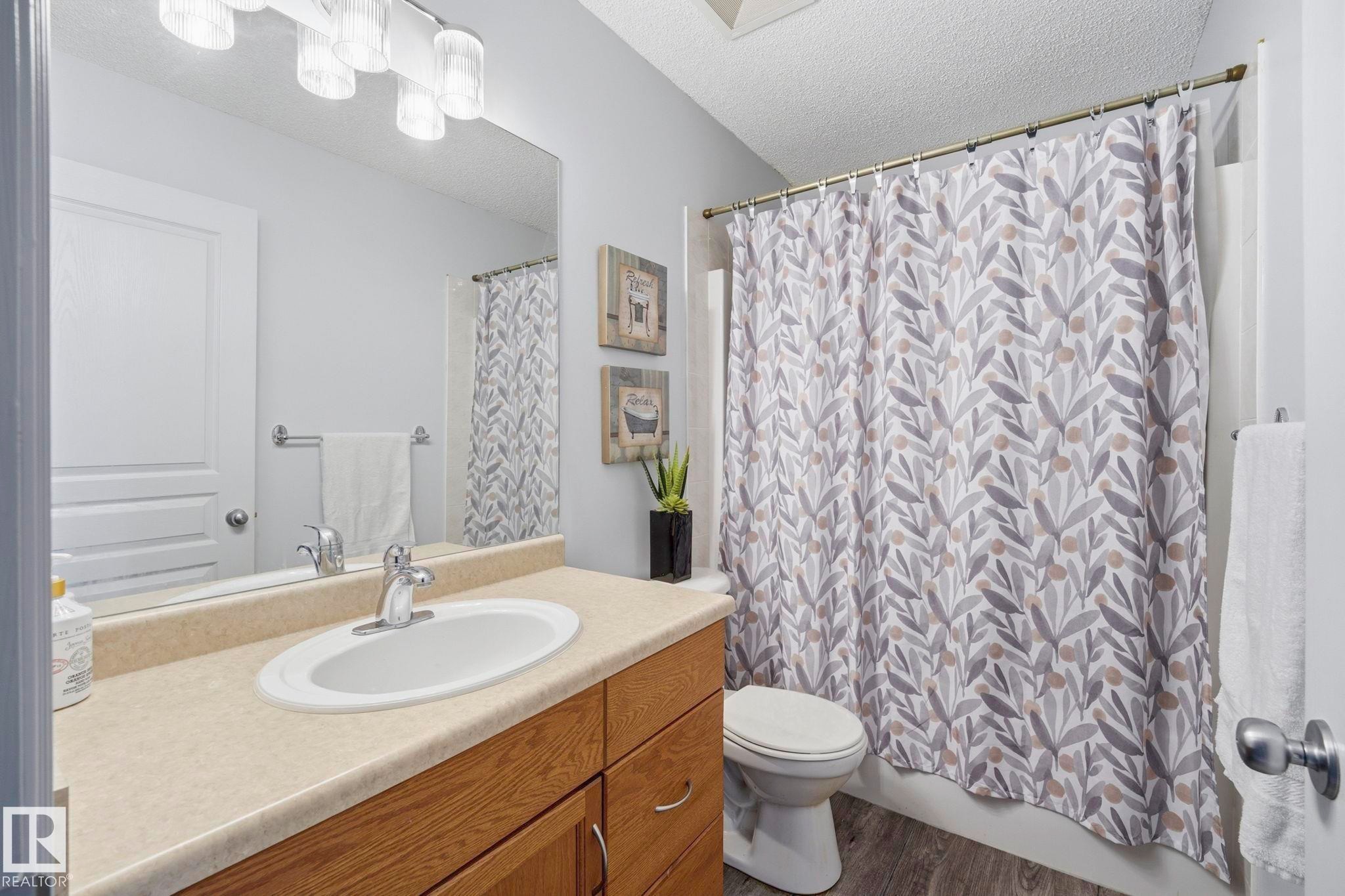 Bathroom featuring a vanity with a light-toned countertop, an integrated sink, and wood-finish cabinetry - 3231 28A Avenue Nw, Edmonton, AB - Indoor Photo Showing Bathroom