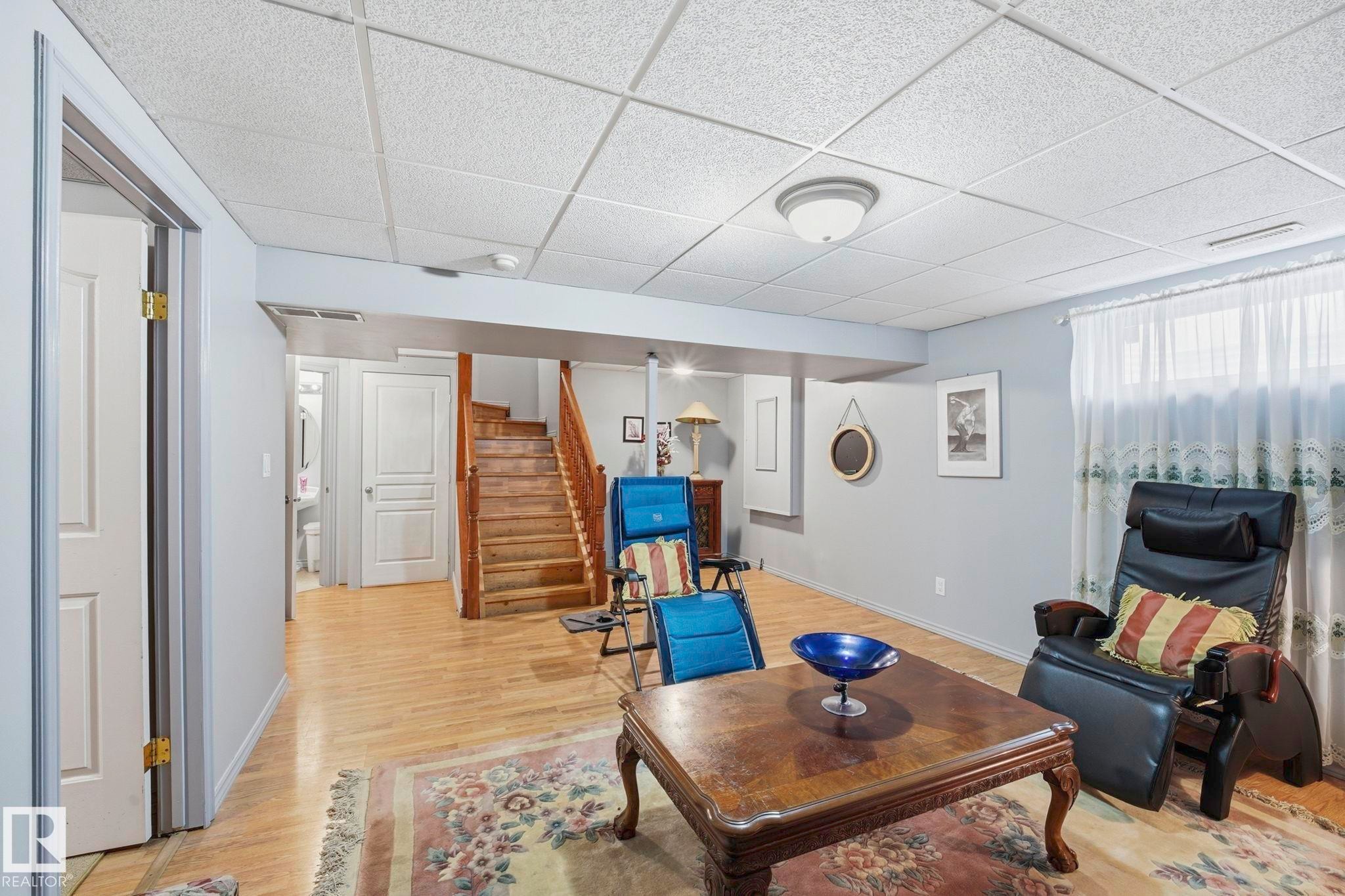 Open-concept room featuring wood-finish flooring, light grey wall paint, and a white acoustical tile ceiling - 3231 28A Avenue Nw, Edmonton, AB - Indoor