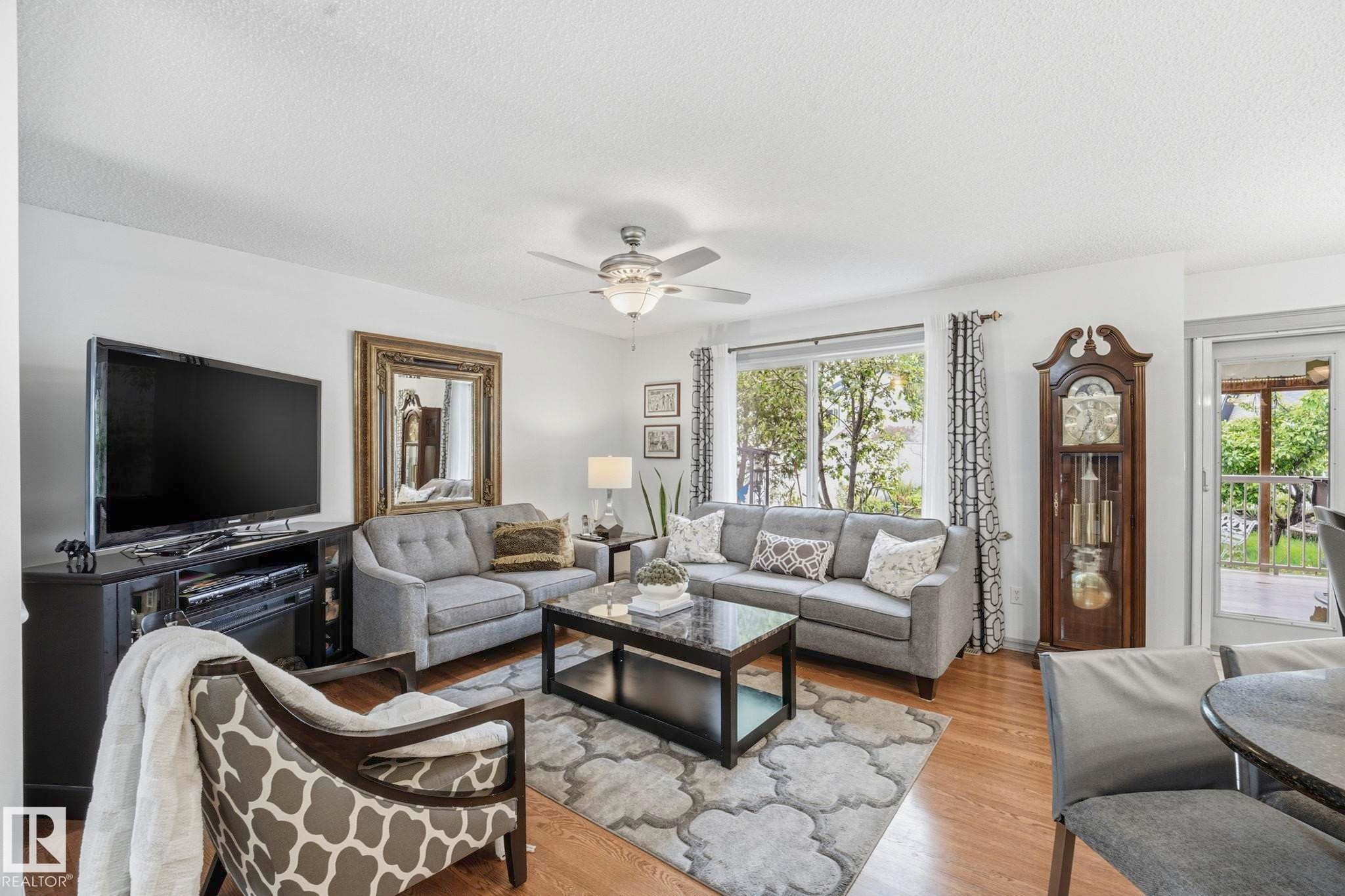 Bright living area featuring wood-finish flooring, a ceiling fan with integrated lighting, and white walls - 3231 28A Avenue Nw, Edmonton, AB - Indoor Photo Showing Living Room