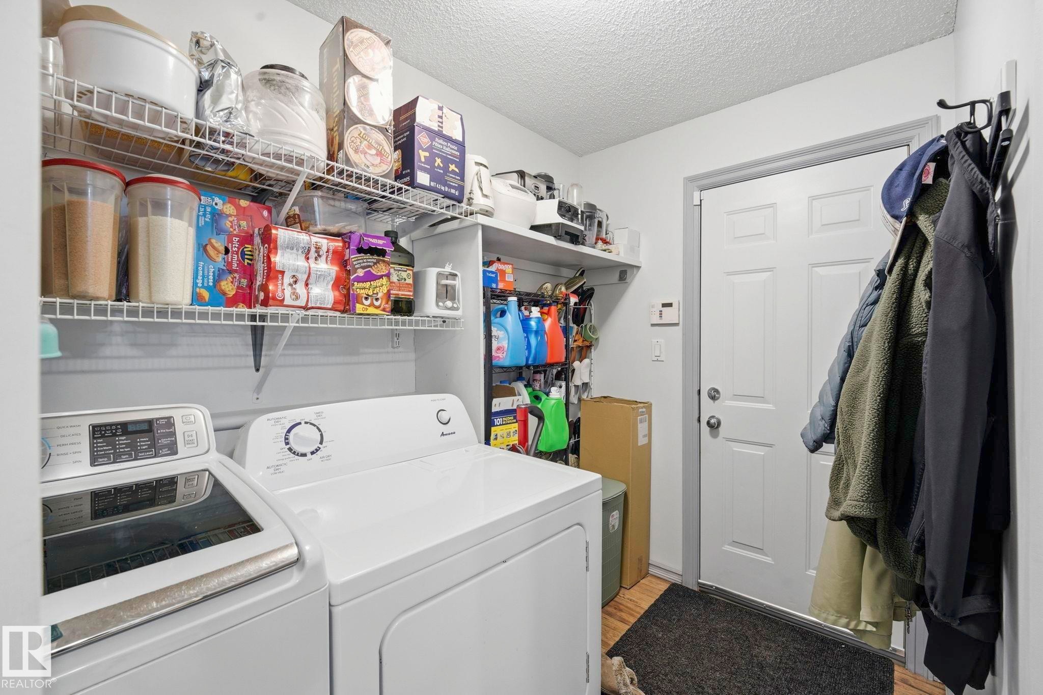 Dedicated utility area featuring a white paneled door, wood-finish flooring, and a wall-mounted coat rack - 3231 28A Avenue Nw, Edmonton, AB - Indoor Photo Showing Laundry Room