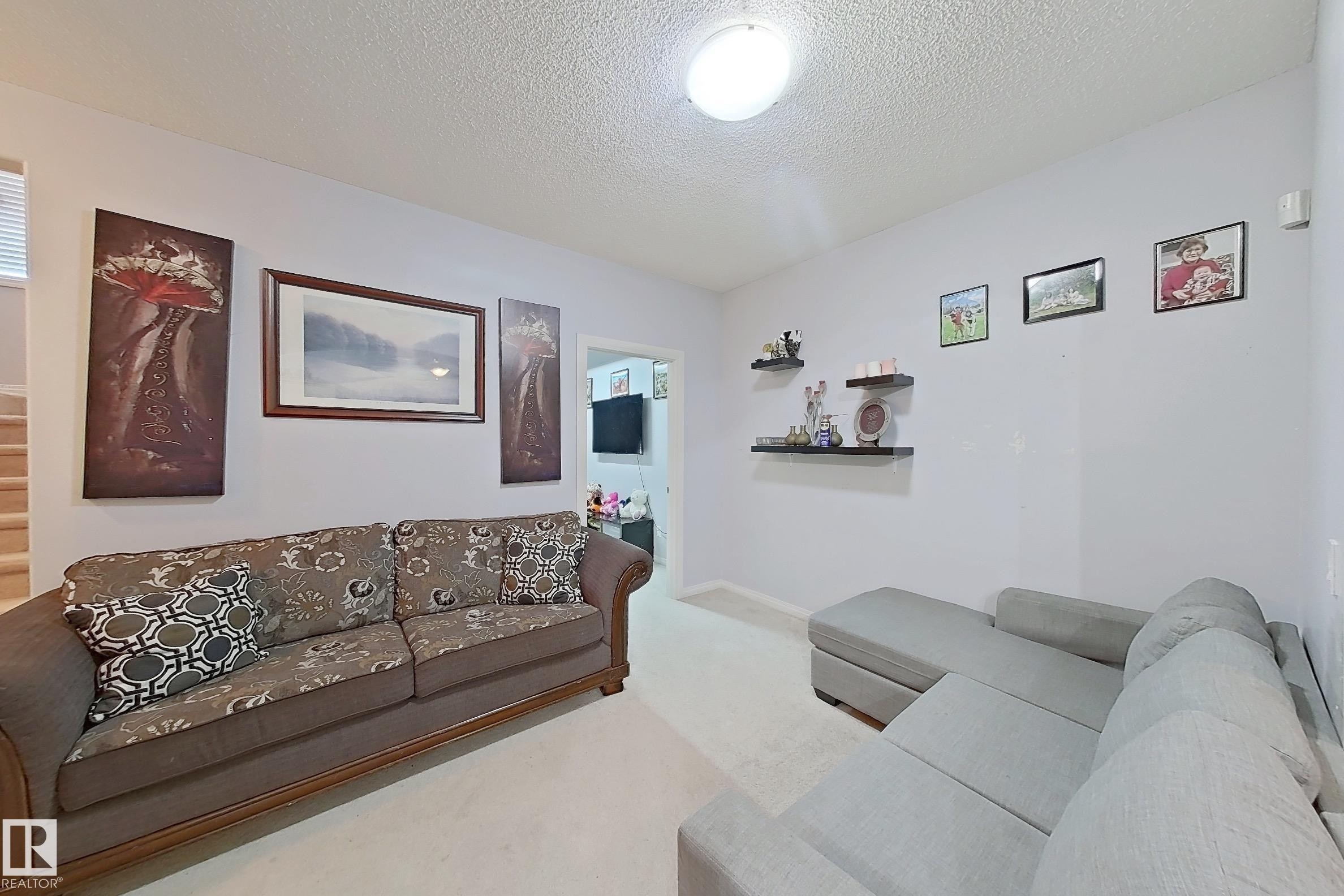 Living area featuring light wall paint, carpet flooring, and a flush-mount ceiling light - 41 5102 30 Avenue, Beaumont, AB
