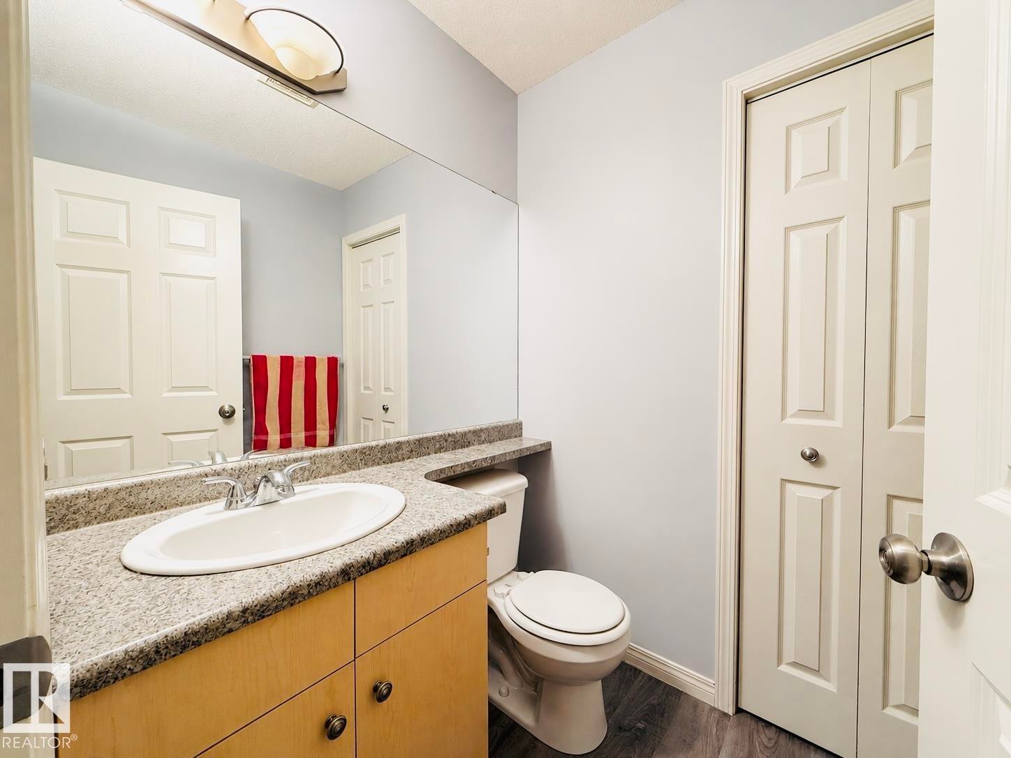 Bathroom featuring a vanity with a granite-look countertop, an oval undermount sink, and wood-finish cabinetry - 41 5102 30 Avenue, Beaumont, AB
