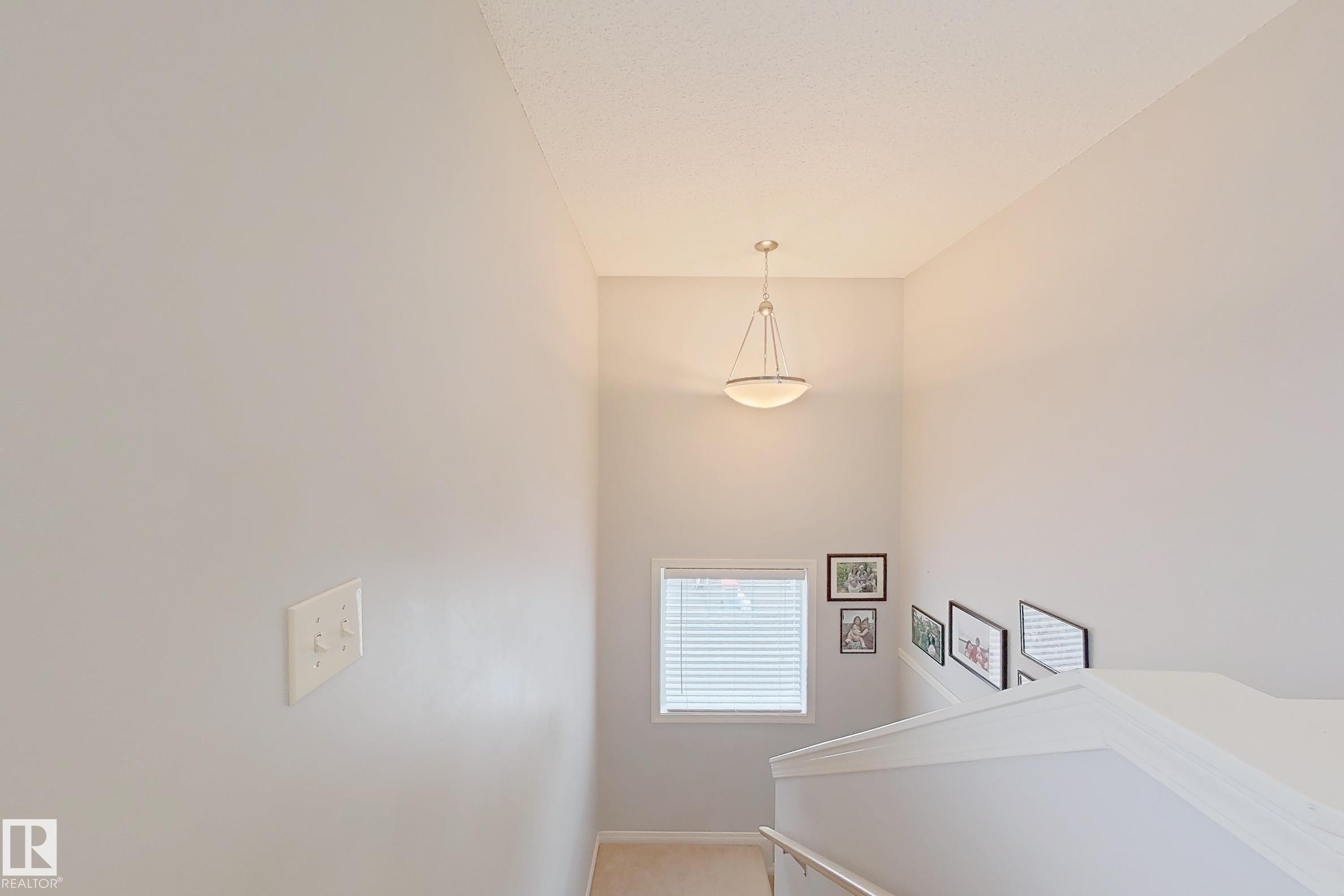 Stairwell featuring light gray walls, a window with horizontal blinds, and a semi-flush mount ceiling light fixture - 41 5102 30 Avenue, Beaumont, AB