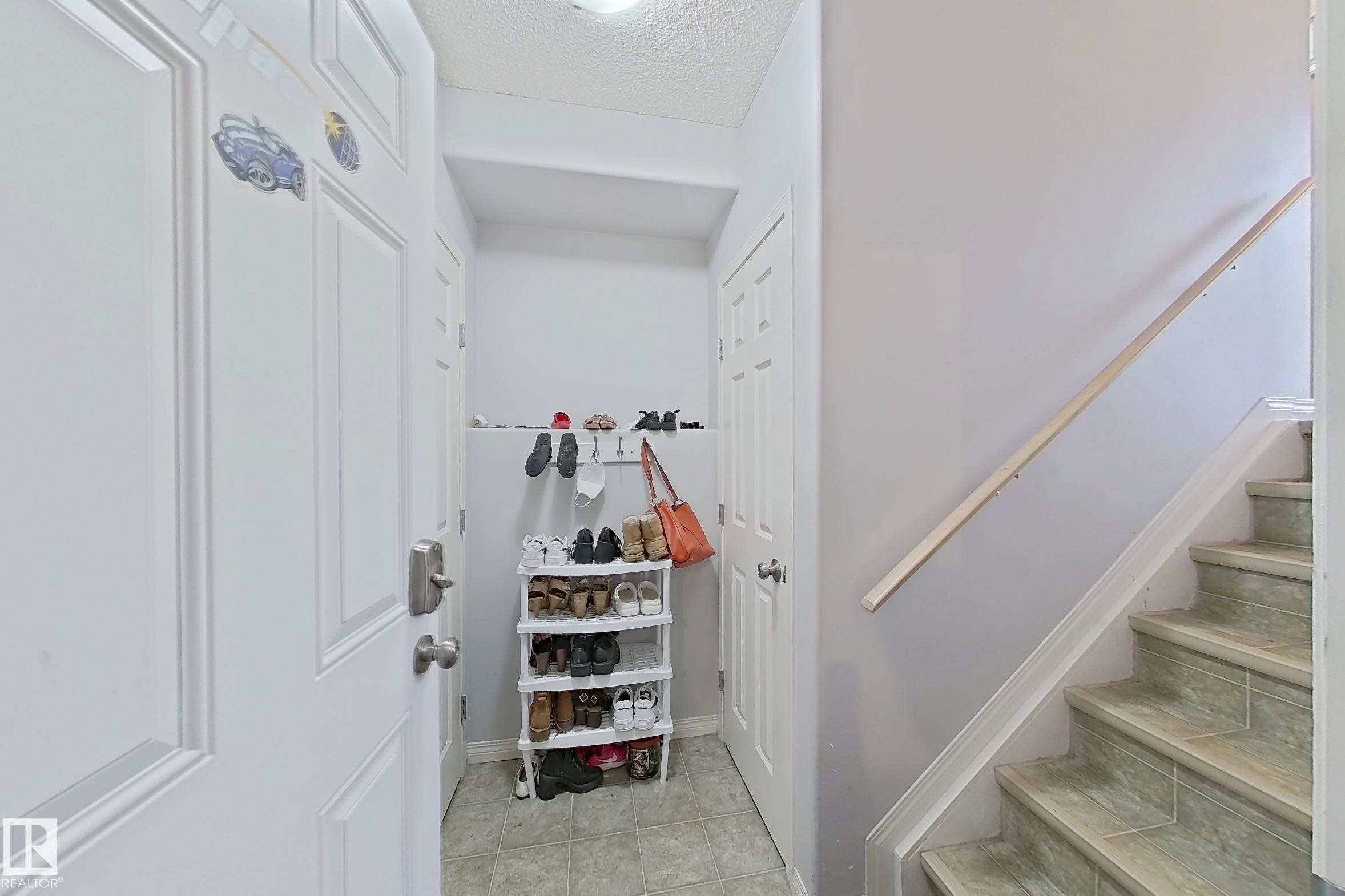 Entryway featuring a white paneled door, light-toned wall paint, and tile flooring - 41 5102 30 Avenue, Beaumont, AB