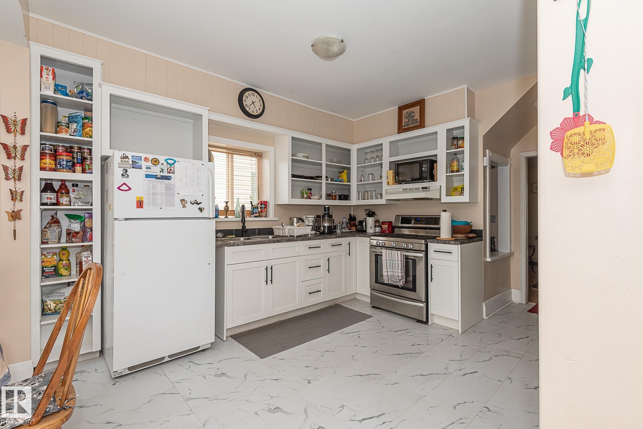Kitchen featuring white cabinetry, dark countertops, and stainless steel appliances - 9623 110A Avenue, Edmonton, AB