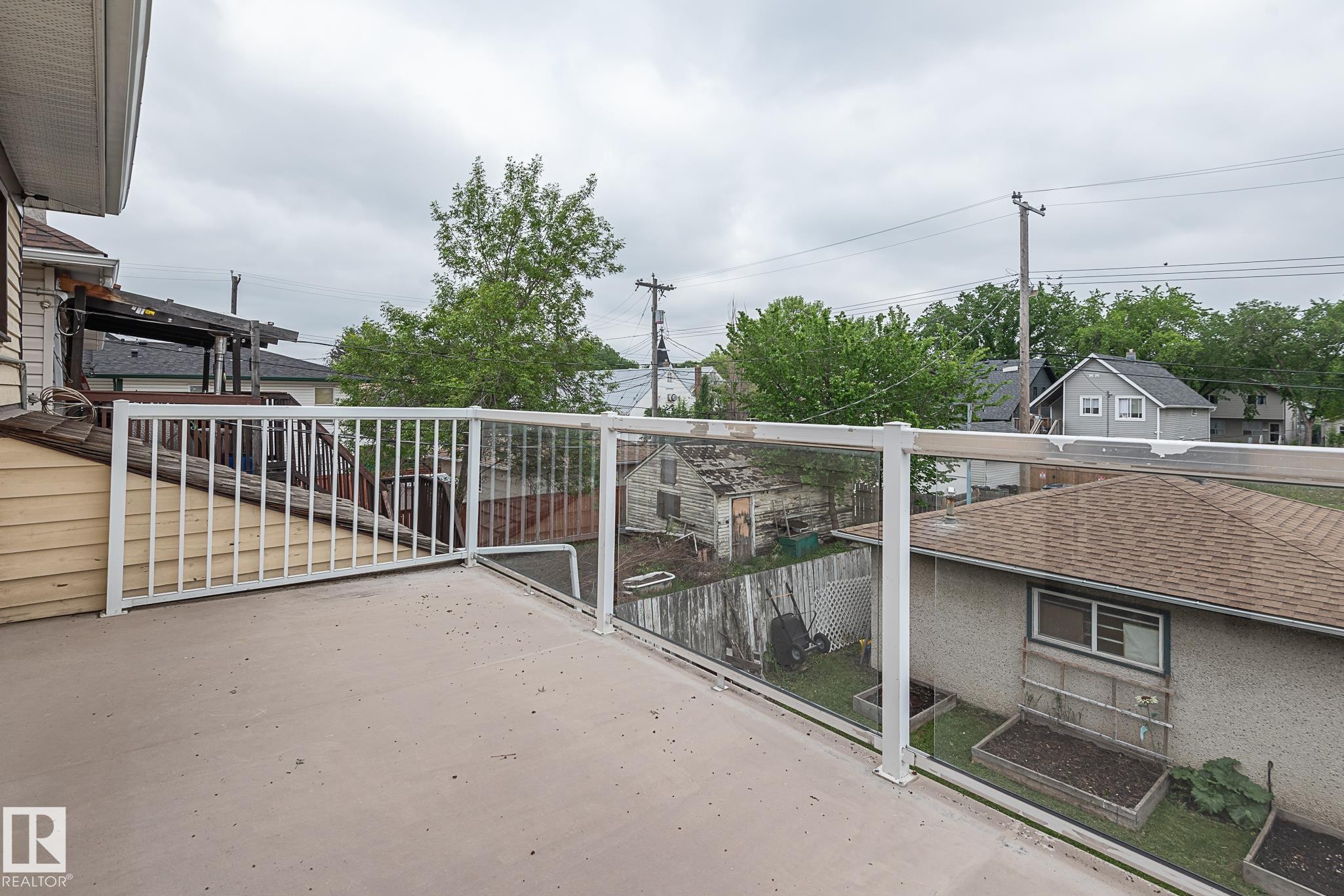 Spacious outdoor deck featuring a light gray surface and white railing with clear panels - 9623 110A Avenue, Edmonton, AB