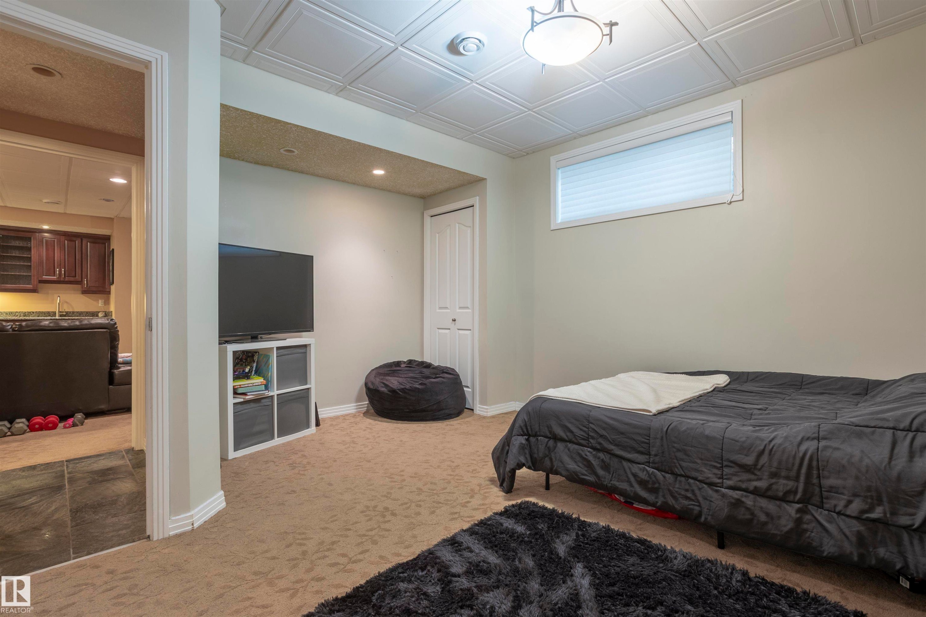 Carpeted room with a drop ceiling featuring recessed lighting and a single window with blinds - 1441 Highwood Boulevard, Devon, AB