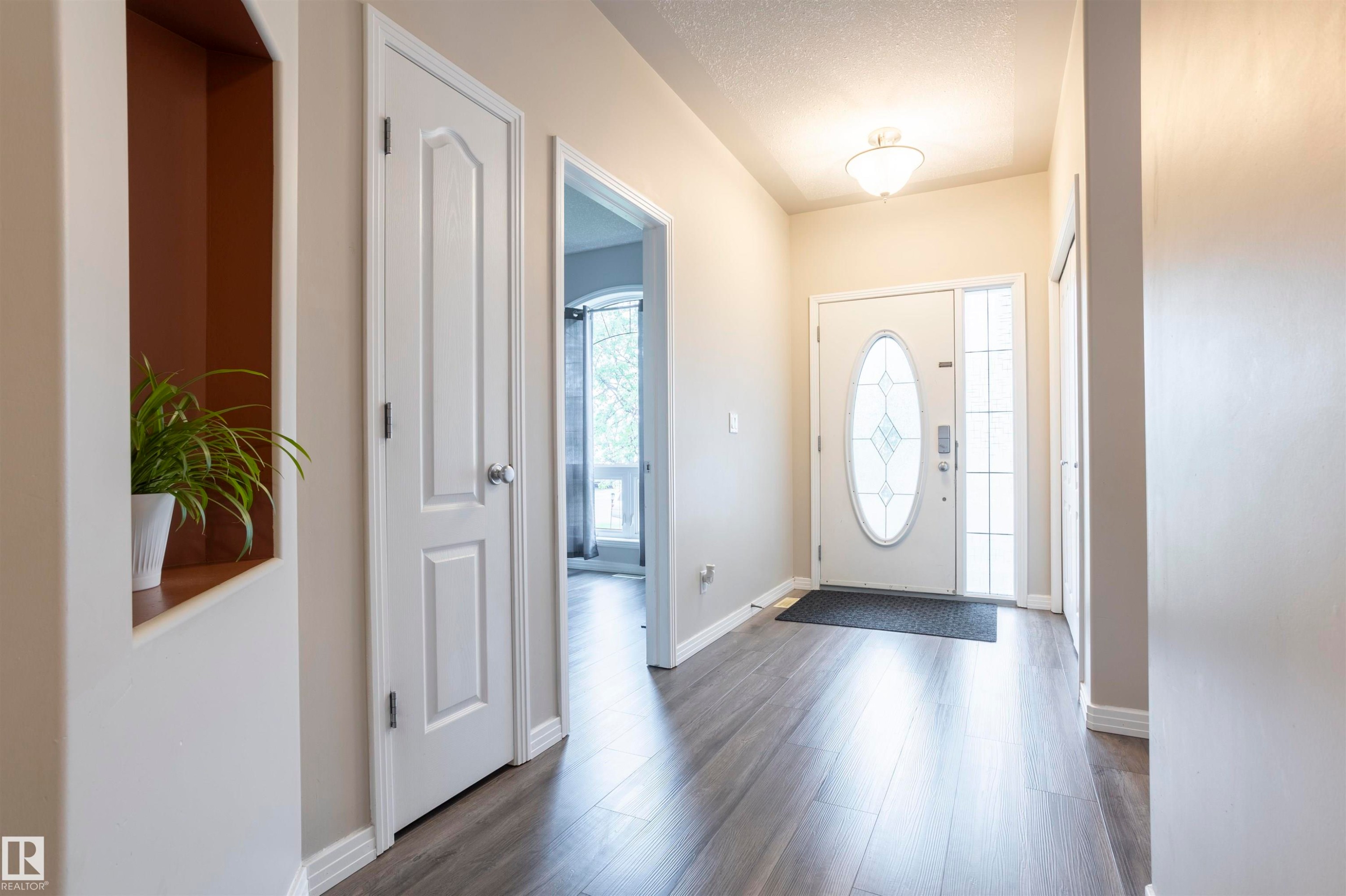 Foyer featuring wood-finish flooring, a white front door with oval frosted glass, and a frosted glass sidelight - 1441 Highwood Boulevard, Devon, AB