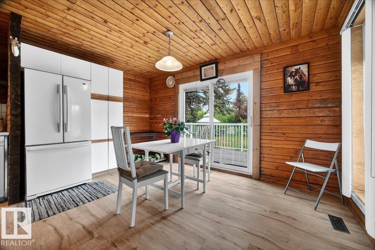 Kitchen area featuring wood-finish flooring, plank wood ceiling, and panel wood walls - 140 50047 Rge Rd 244, Rural Leduc County, AB