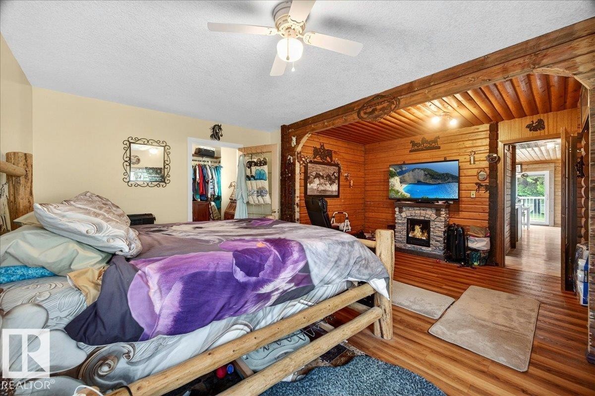 Accent wall featuring horizontal wood paneling and a stone-clad fireplace with hearth - 140 50047 Rge Rd 244, Rural Leduc County, AB