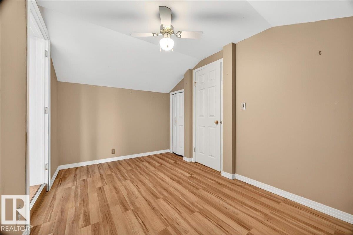 Interior room featuring wood-finish flooring, two panel doors, and a ceiling fan with integrated lighting - 140 50047 Rge Rd 244, Rural Leduc County, AB