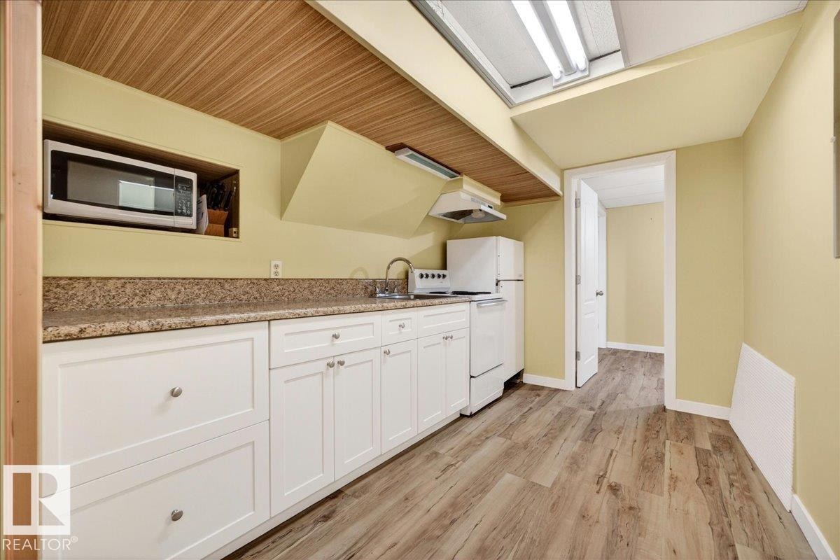 Kitchenette featuring a wood-finish ceiling, light wood-finish flooring, white cabinetry, speckled countertops, and a full-size refrigerator - 140 50047 Rge Rd 244, Rural Leduc County, AB