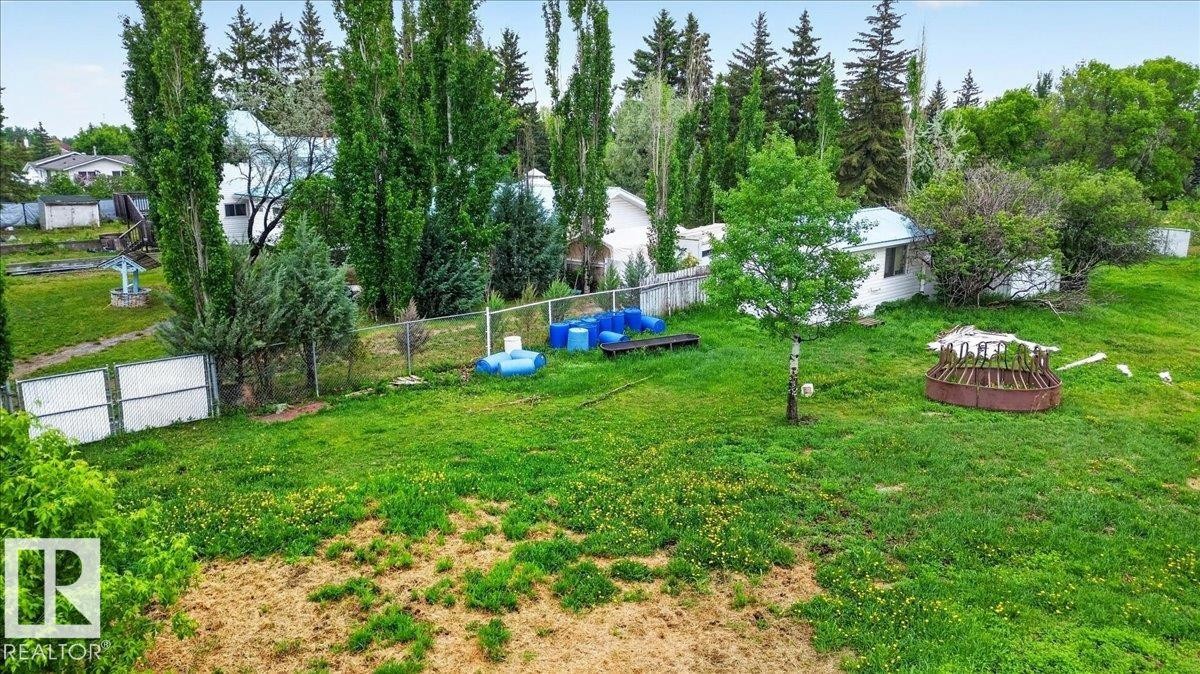 Expansive green space featuring mature trees, a chain-link fence, and a distant structure - 140 50047 Rge Rd 244, Rural Leduc County, AB