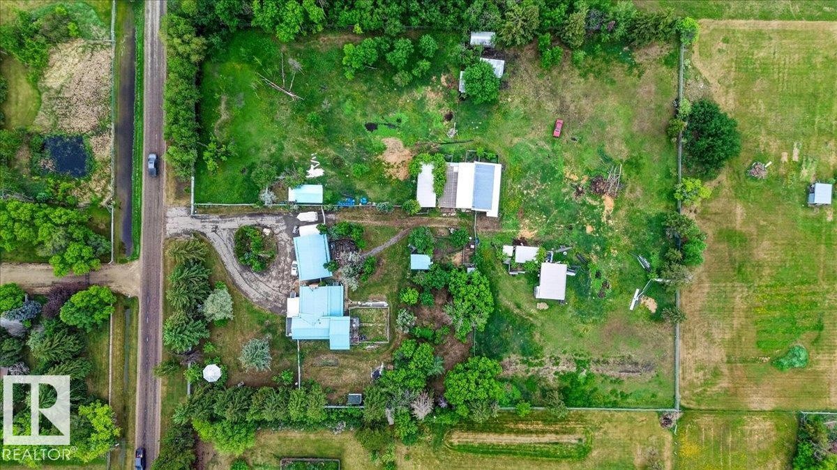 Expansive rural property featuring multiple structures, mature trees, and a dirt road entrance - 140 50047 Rge Rd 244, Rural Leduc County, AB