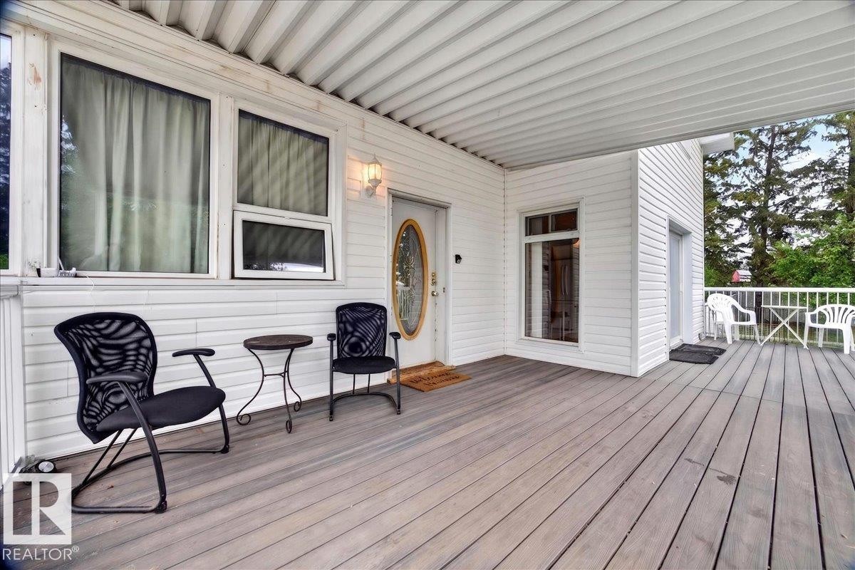 Expansive outdoor deck featuring wood-finish flooring, white siding, and a covered ceiling - 140 50047 Rge Rd 244, Rural Leduc County, AB