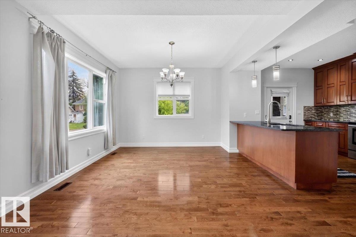 Spacious interior featuring wood-finish flooring, white walls, and abundant natural light from multiple windows - 10958 88 Avenue, Edmonton, AB