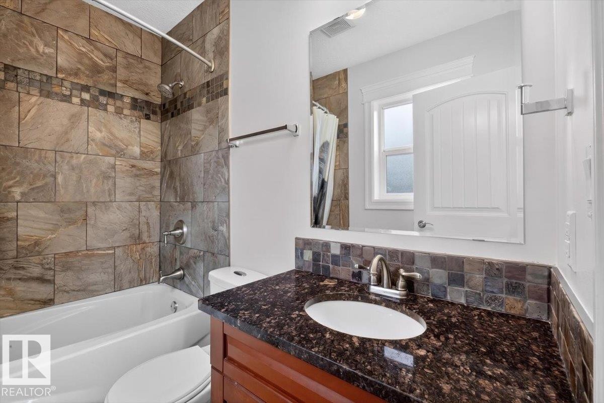 Bathroom featuring a tub/shower combination with large format tiled surround and decorative accent band - 10958 88 Avenue, Edmonton, AB