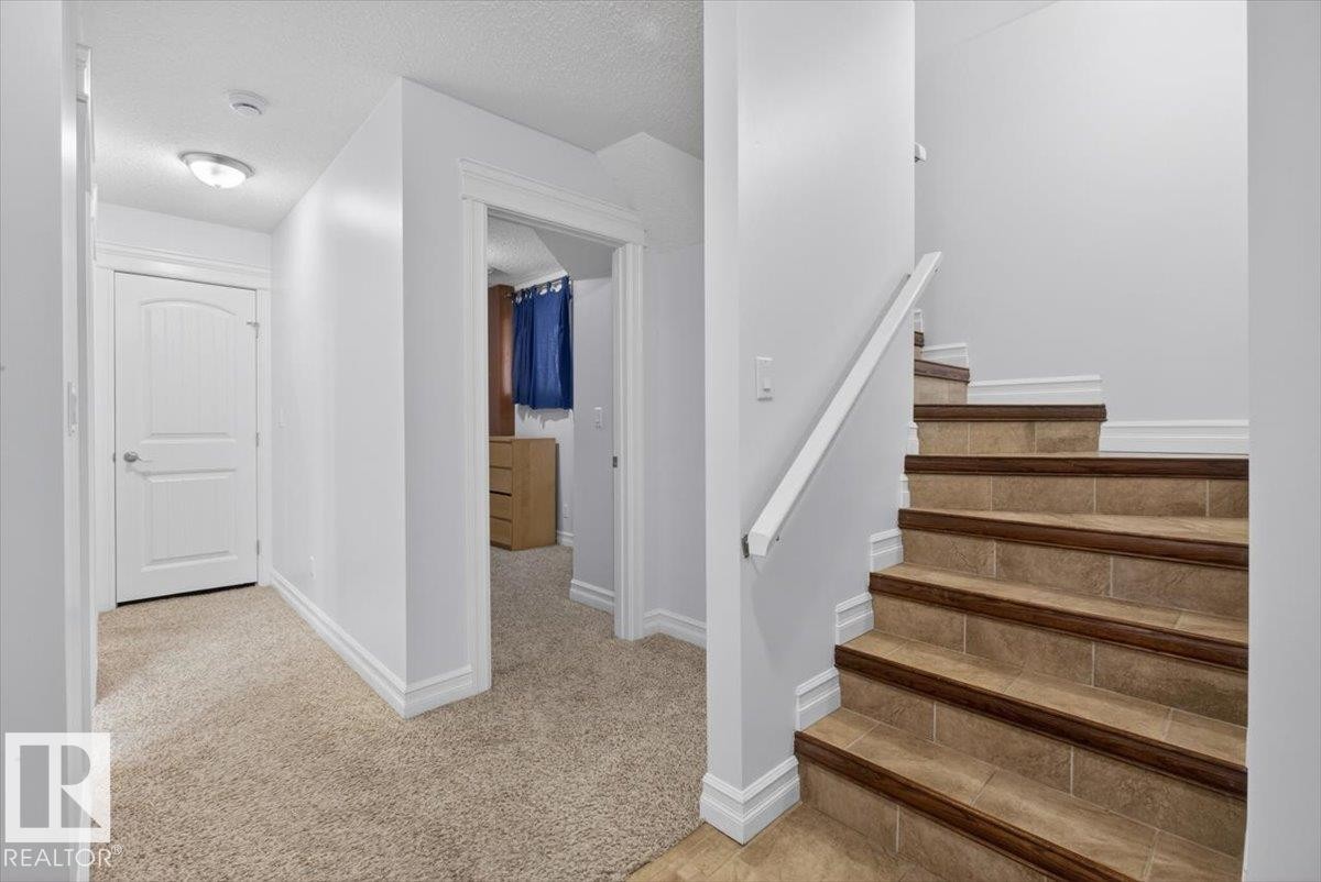 Staircase featuring tile treads with wood-finish nosing and a white handrail - 10958 88 Avenue, Edmonton, AB