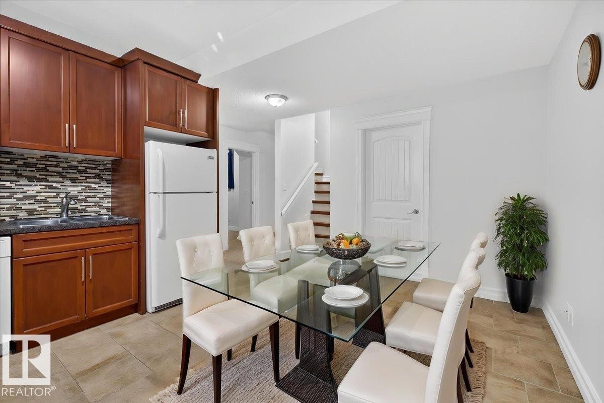Compact kitchen area featuring wood-finish cabinetry, a patterned tile backsplash, and dark countertops - 10958 88 Avenue, Edmonton, AB