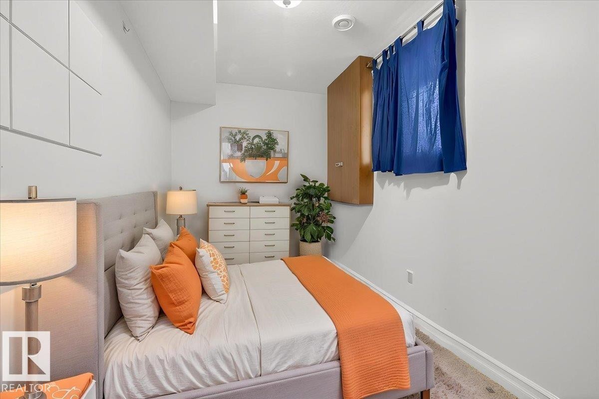 Bedroom featuring a tufted fabric headboard, recessed lighting, and a window with blue drapes - 10958 88 Avenue, Edmonton, AB