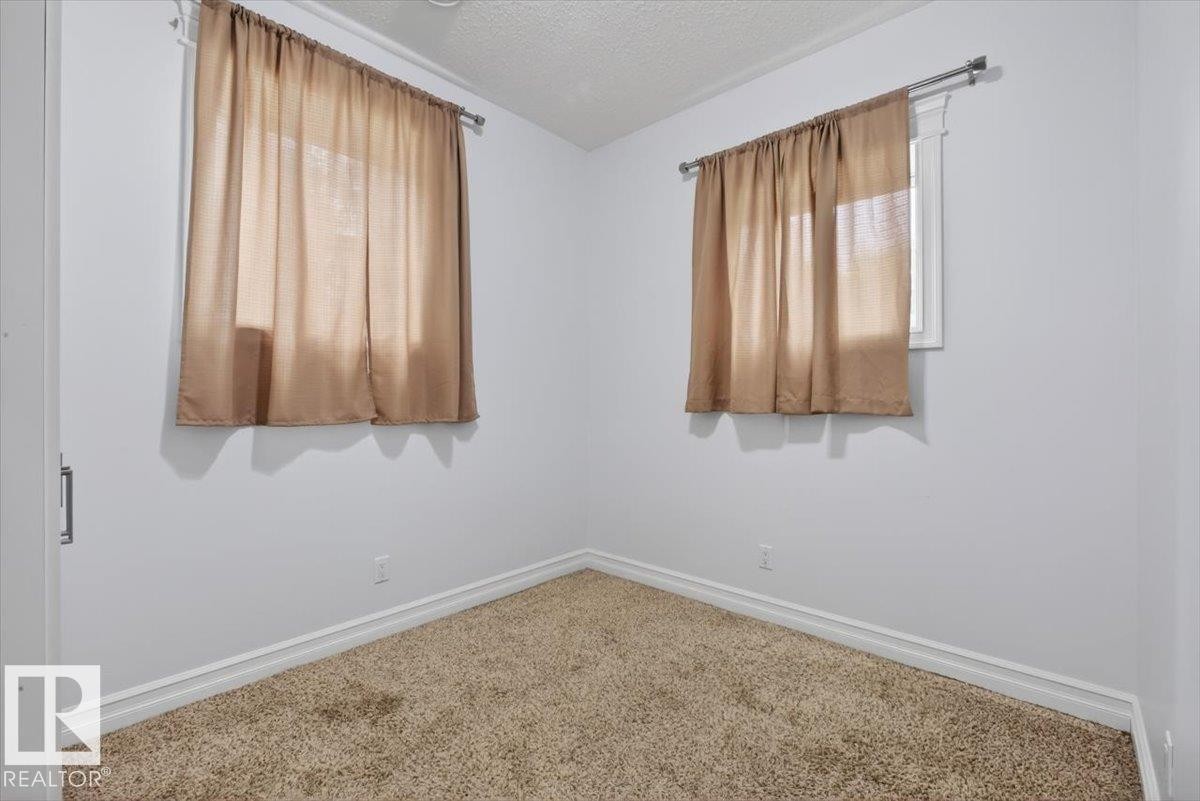 Carpeted room with white walls, two windows, and white trim - 10958 88 Avenue, Edmonton, AB