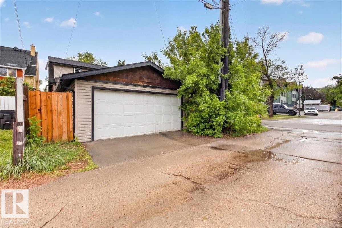 Detached garage featuring a white overhead door, horizontal siding, and wood-shingle accents - 10958 88 Avenue, Edmonton, AB
