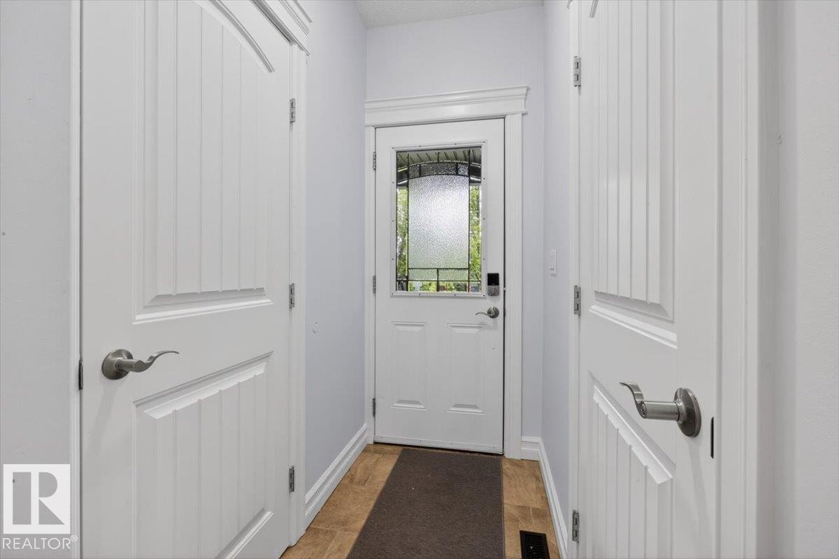 Entryway featuring a white paneled door with decorative glass, two white interior paneled doors, and wood-finish flooring - 10958 88 Avenue, Edmonton, AB