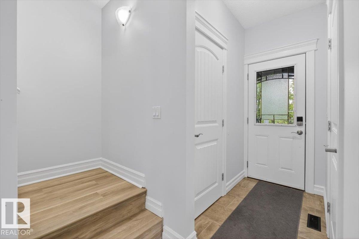 Entryway featuring a white door with decorative glass inserts, ceramic tile flooring, and a built-in coat closet - 10958 88 Avenue, Edmonton, AB