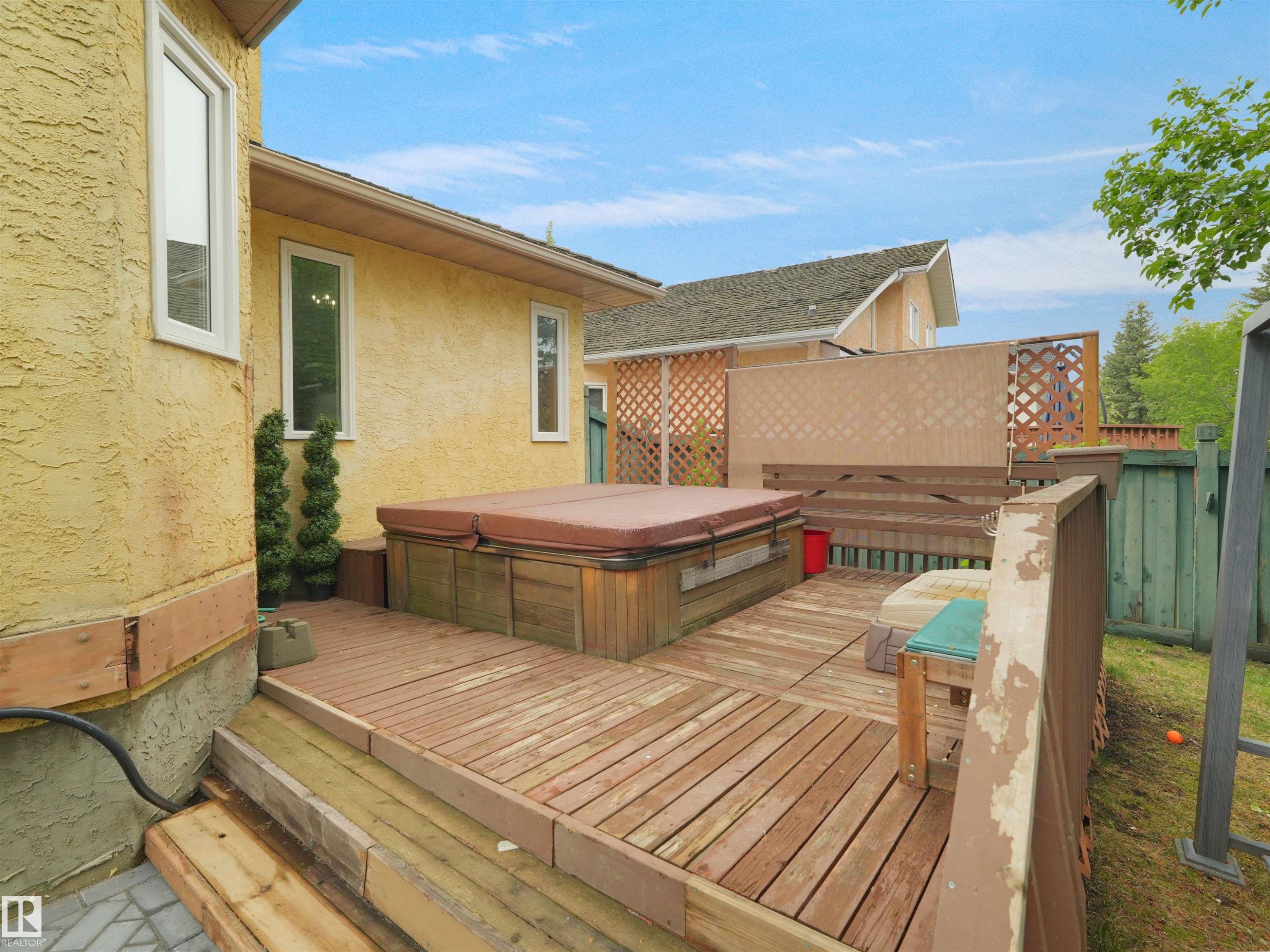 Outdoor wooden deck featuring a built-in hot tub, privacy screening, and partial lattice fence - 208 Ferguson Place, Edmonton, AB