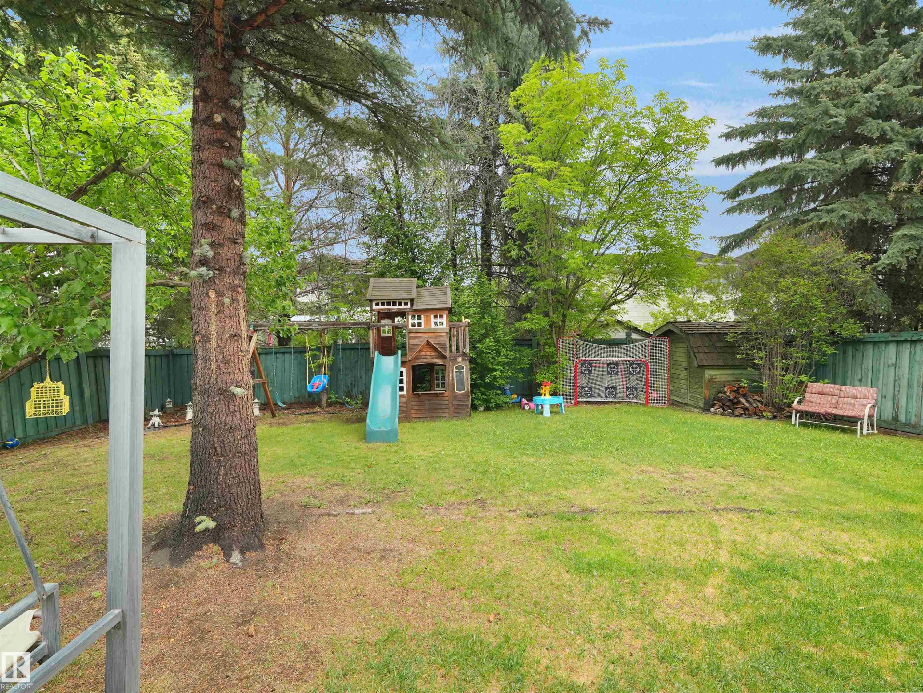 Expansive backyard featuring a manicured lawn, established trees, and a wooden storage shed - 208 Ferguson Place, Edmonton, AB