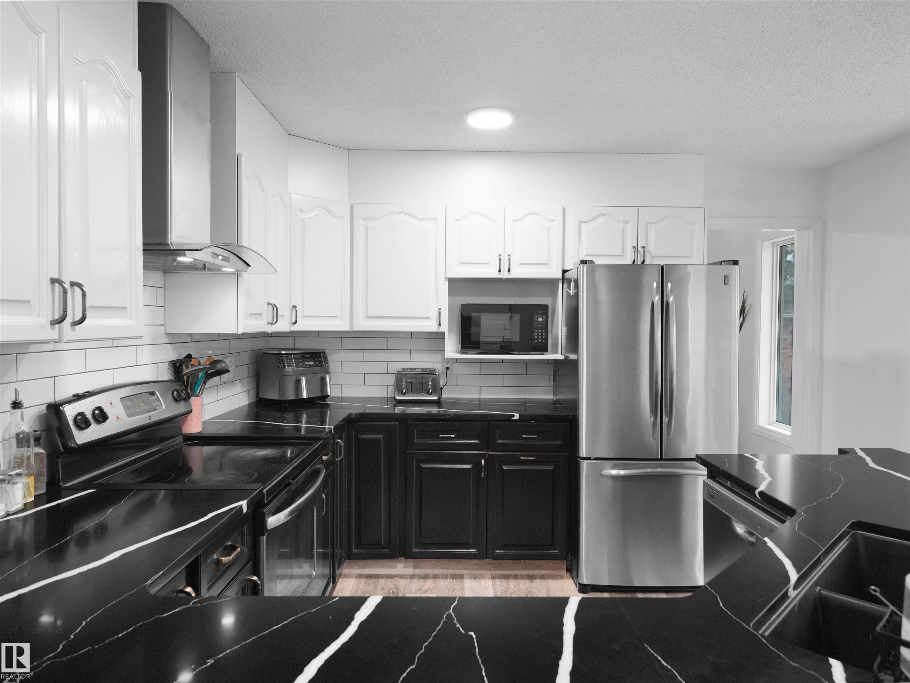 Kitchen featuring black countertops with white veining, white upper cabinetry, and contrasting black lower cabinetry - 208 Ferguson Place, Edmonton, AB