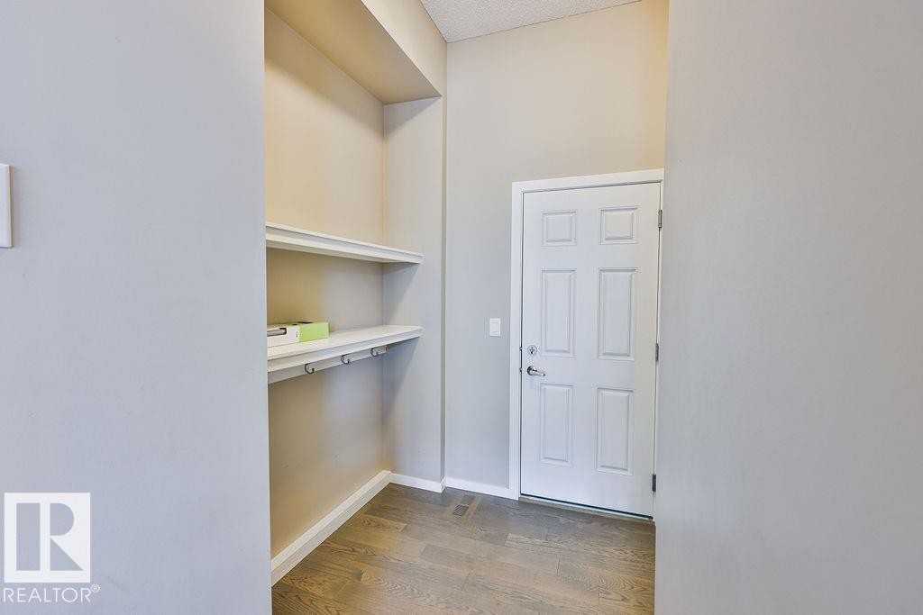 Mudroom area featuring wood-finish flooring, light gray walls, and a multi-paneled door - 2031 207 Street, Edmonton, AB