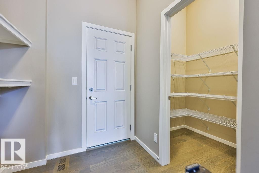 Functional entryway featuring a paneled door, wood-finish flooring, and built-in shelving - 2031 207 Street, Edmonton, AB