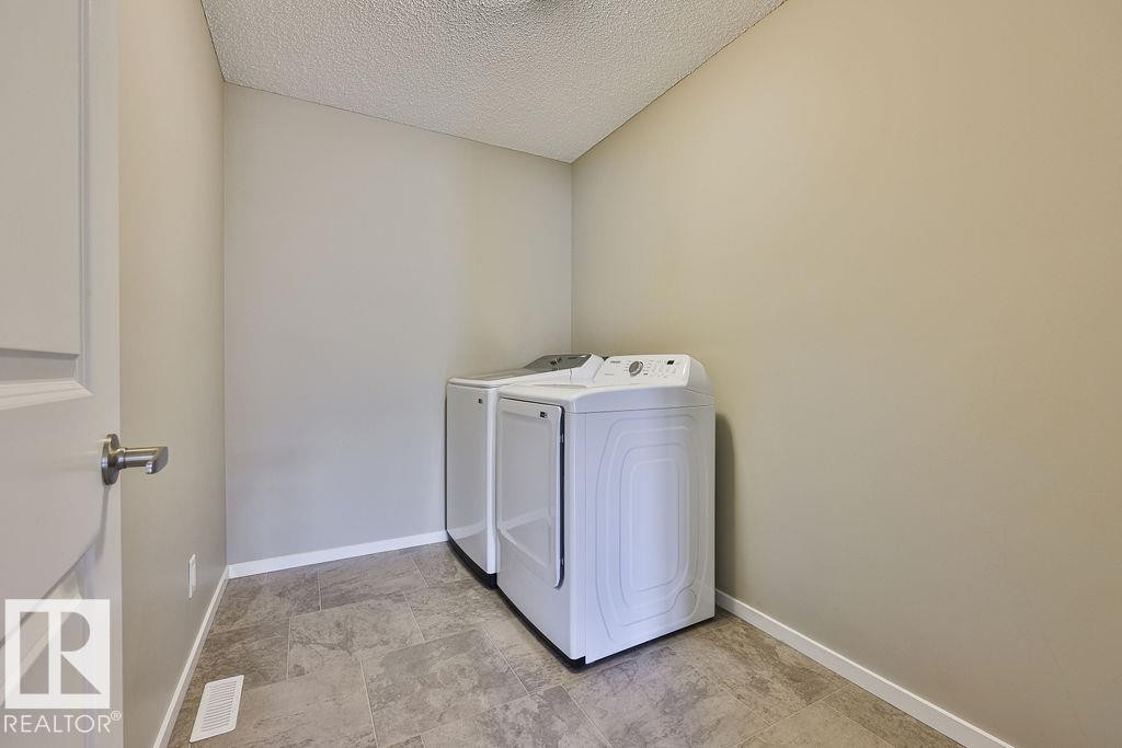 Dedicated laundry area featuring durable tile flooring, neutral wall paint, and white baseboards - 2031 207 Street, Edmonton, AB