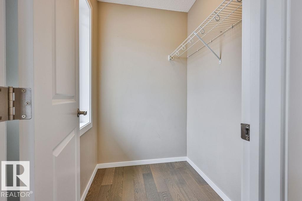 Closet space featuring wood-finish flooring, neutral-toned walls, and a white wire shelving system - 2031 207 Street, Edmonton, AB